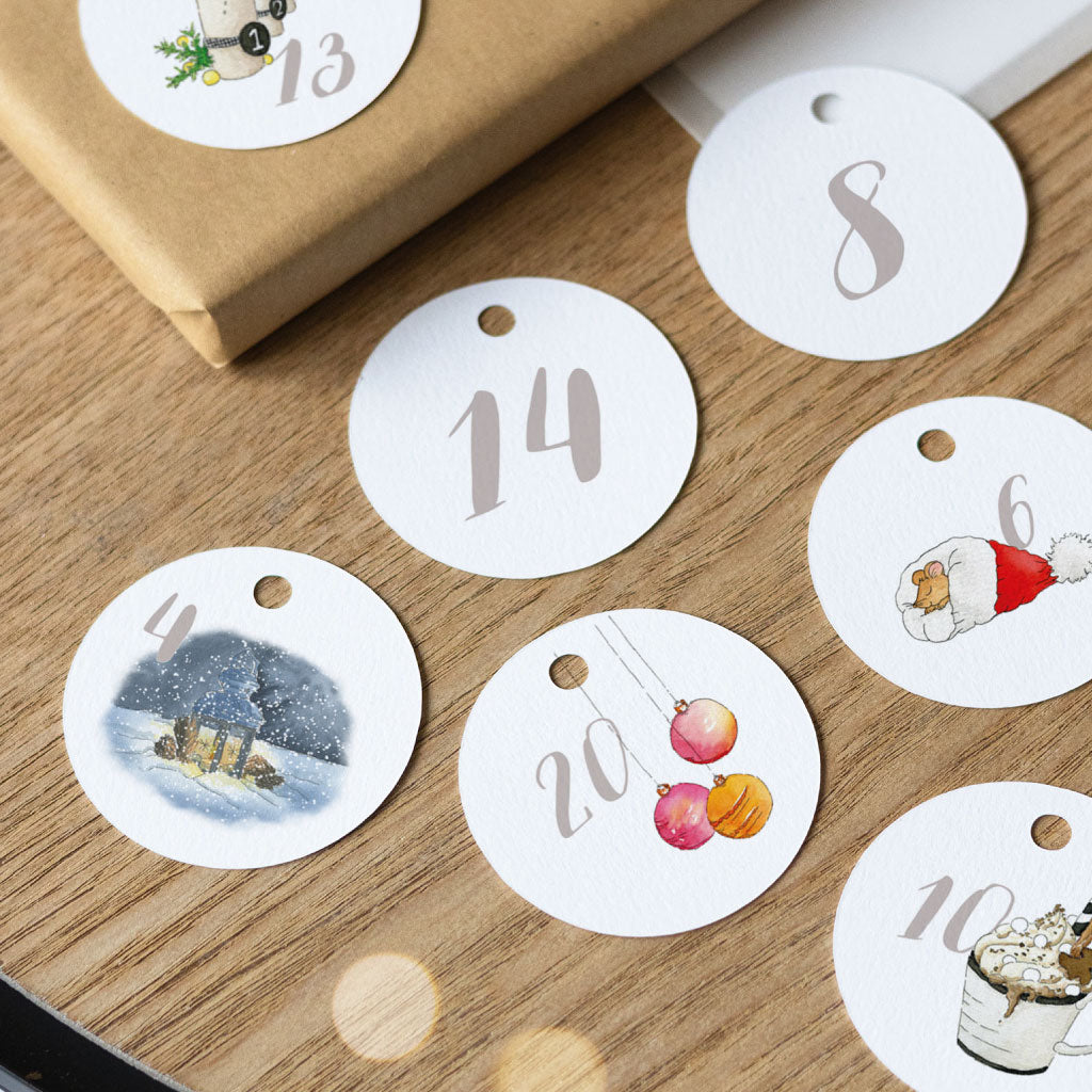 Runde DIY-Adventskalender-Anhänger: Zahl 4 mit verschneitem Haus, Zahl 6 mit Nikolausmütze, Zahl 8 ohne Motiv, Zahl 10 mit Heißgetränk, Zahl 13 mit Adventskerzen, Zahl 14 ohne Motiv, Zahl 20 mit Christbaumkugeln