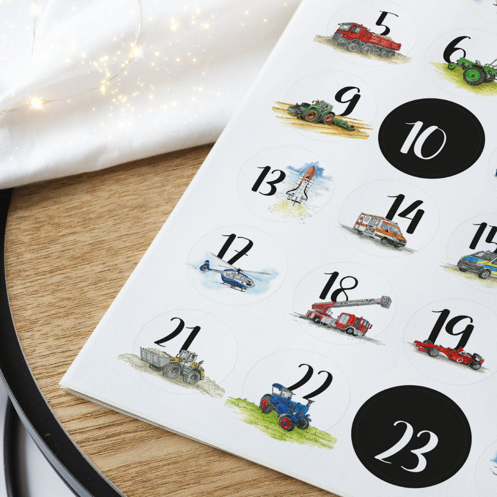 Ein Bogen DIN A4 mit 24 runden Adventskalender Aufklebern liegt auf weihnachtlicher Deko