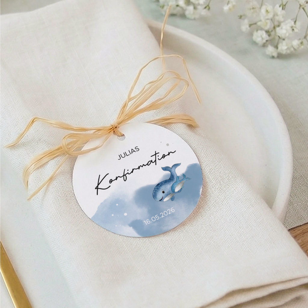 Tischdeko zur Konfirmation mit personalisiertem Namensschild auf einer hellen Serviette und Wal Aquarell Motiv.