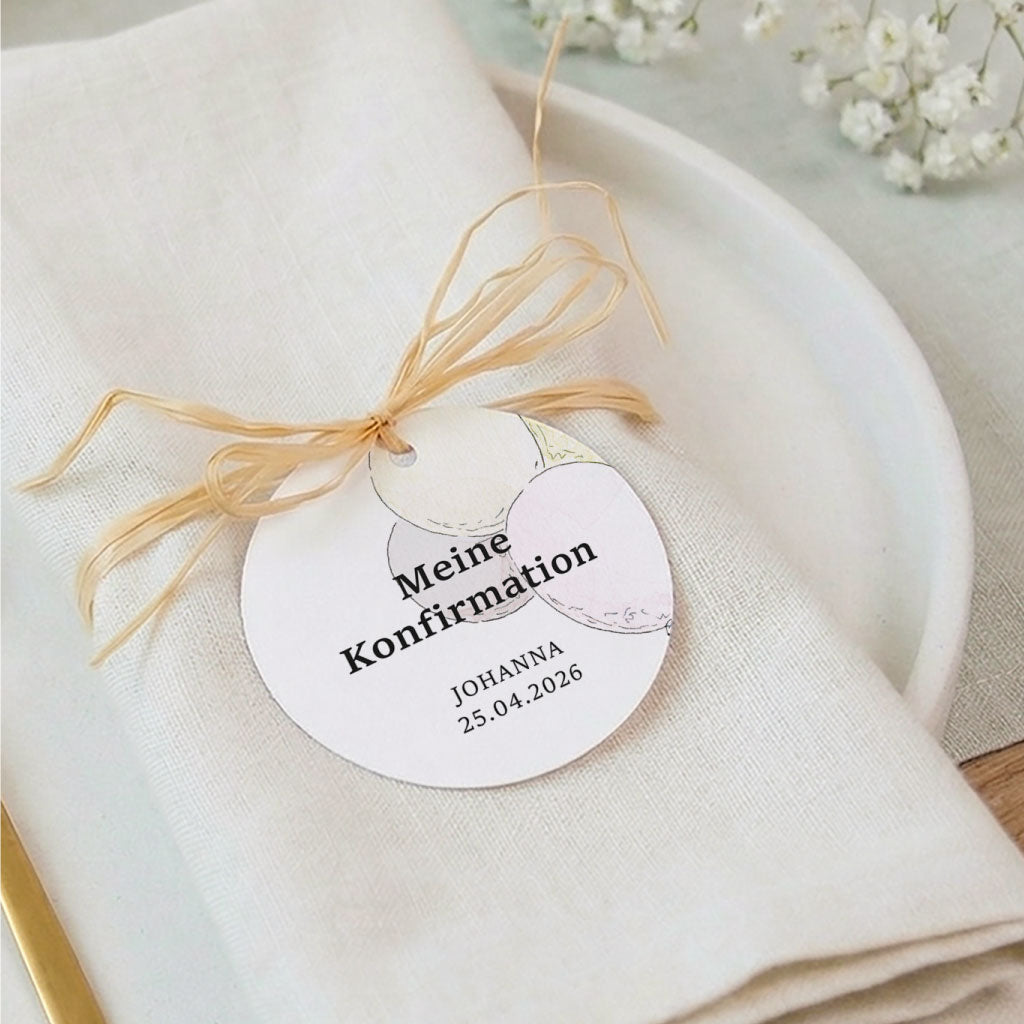 Personalisierter Anhänger zur Konfirmation auf Serviette liegend verziert mit Luftballons.