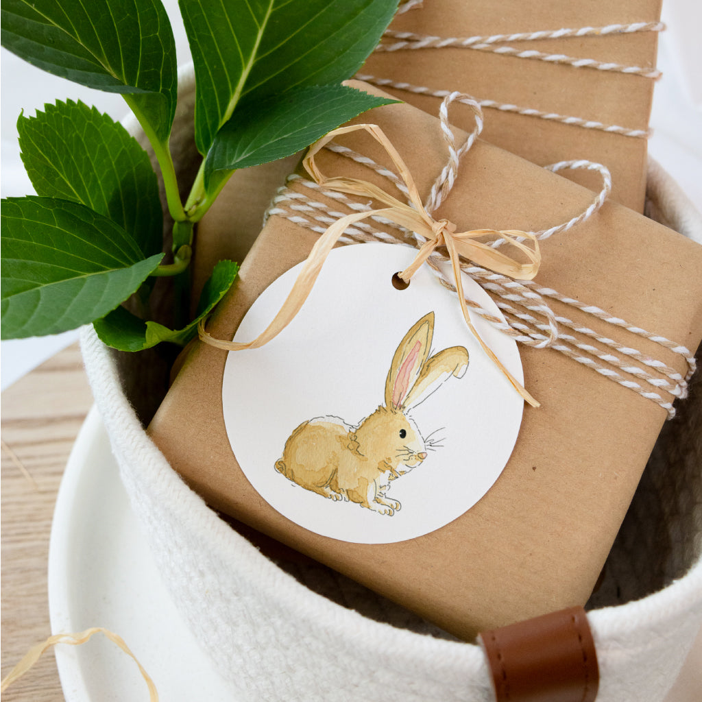 Runder Anhänger mit handgemaltem Aquarell-Osterhasen, liebevoll an Ostergeschenk gebunden – perfekte Osterdekoration.