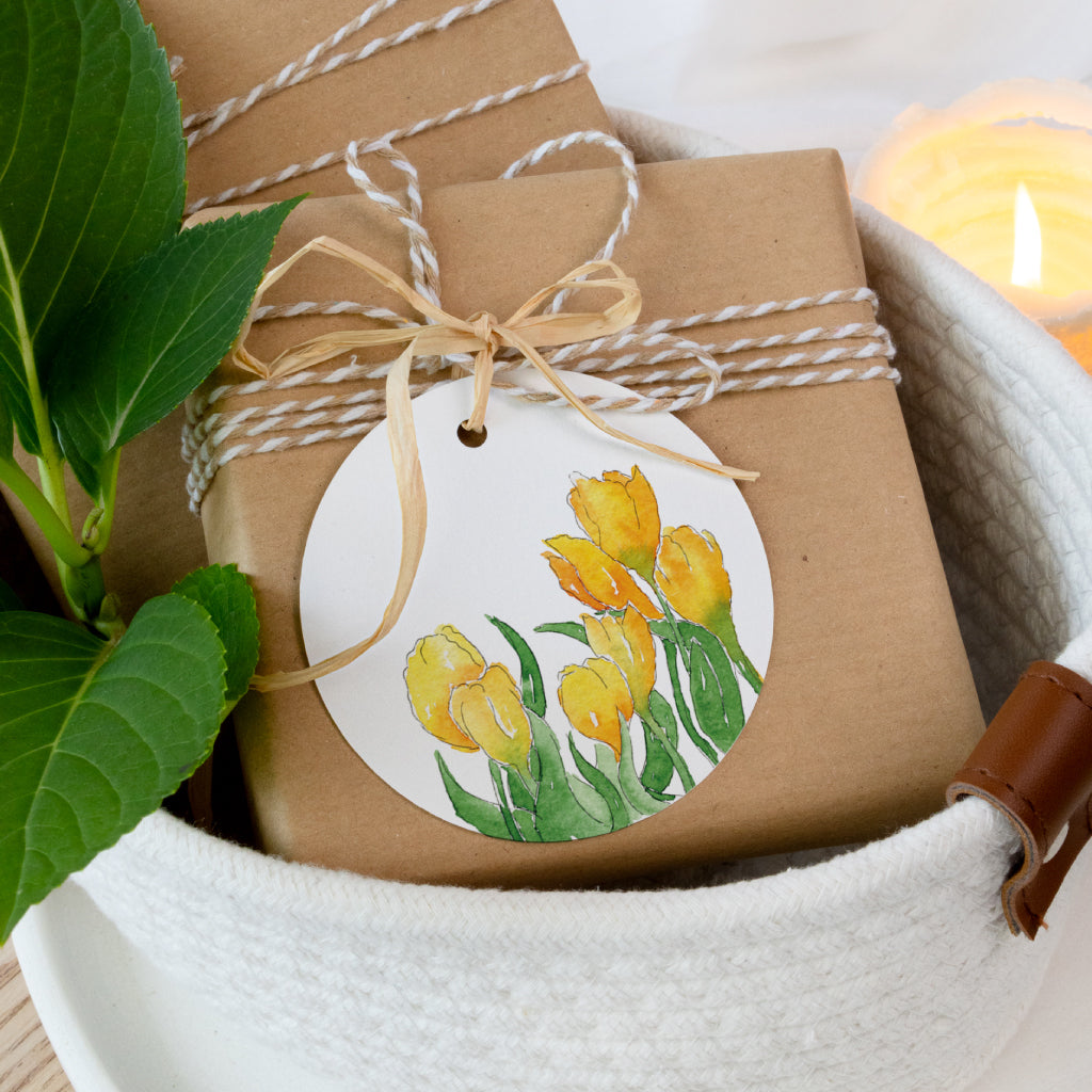 Runder Geschenkanhänger mit gelben Tulpen als Aquarellmotiv, liebevoll an ein Ostergeschenk gebunden – frühlingshafte Osterdekoration.