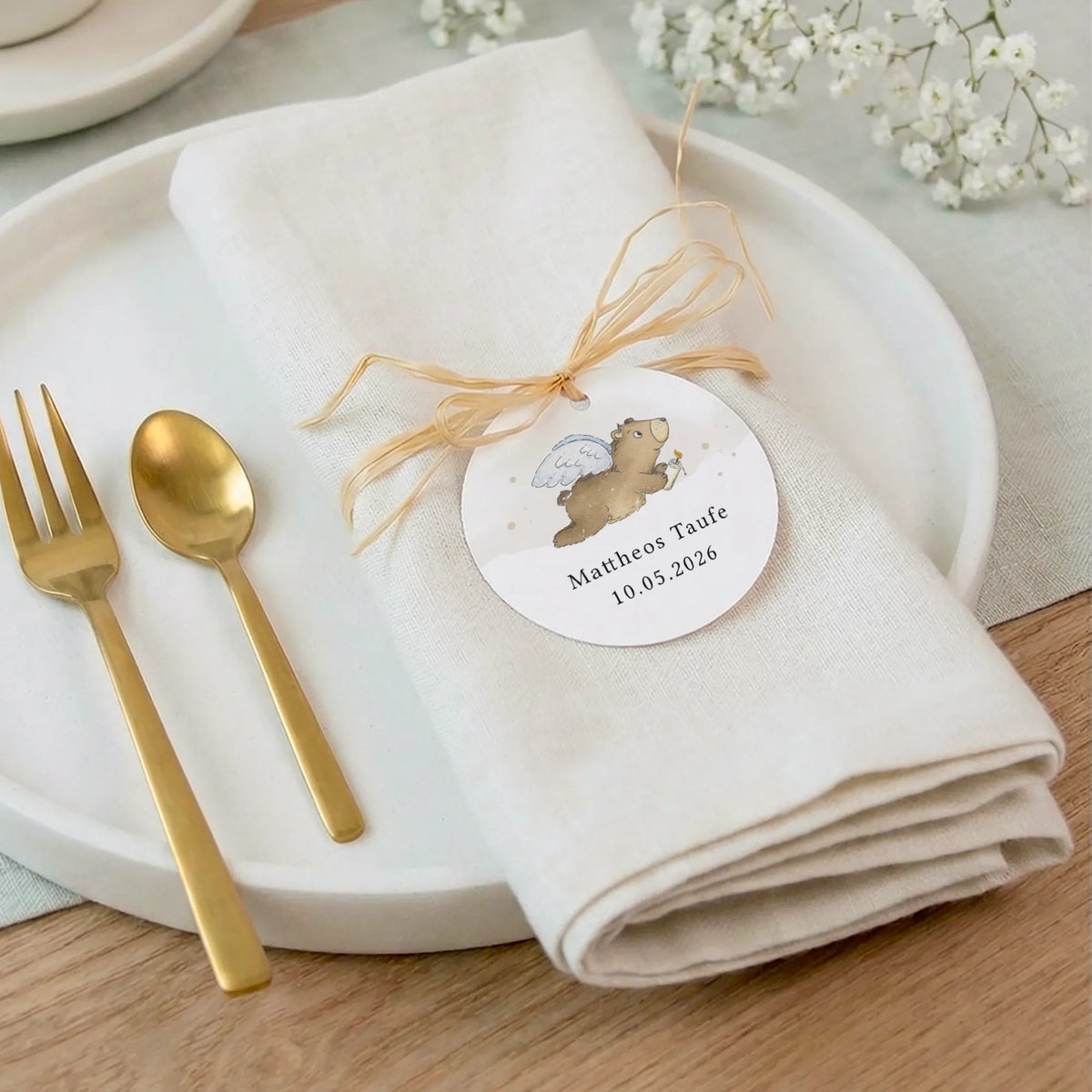 Personalisierter Taufe Anhänger mit Aquarell Motiv Engelbär an Leinenserviette mit Goldbesteck als Tischdeko zur Baby Taufe