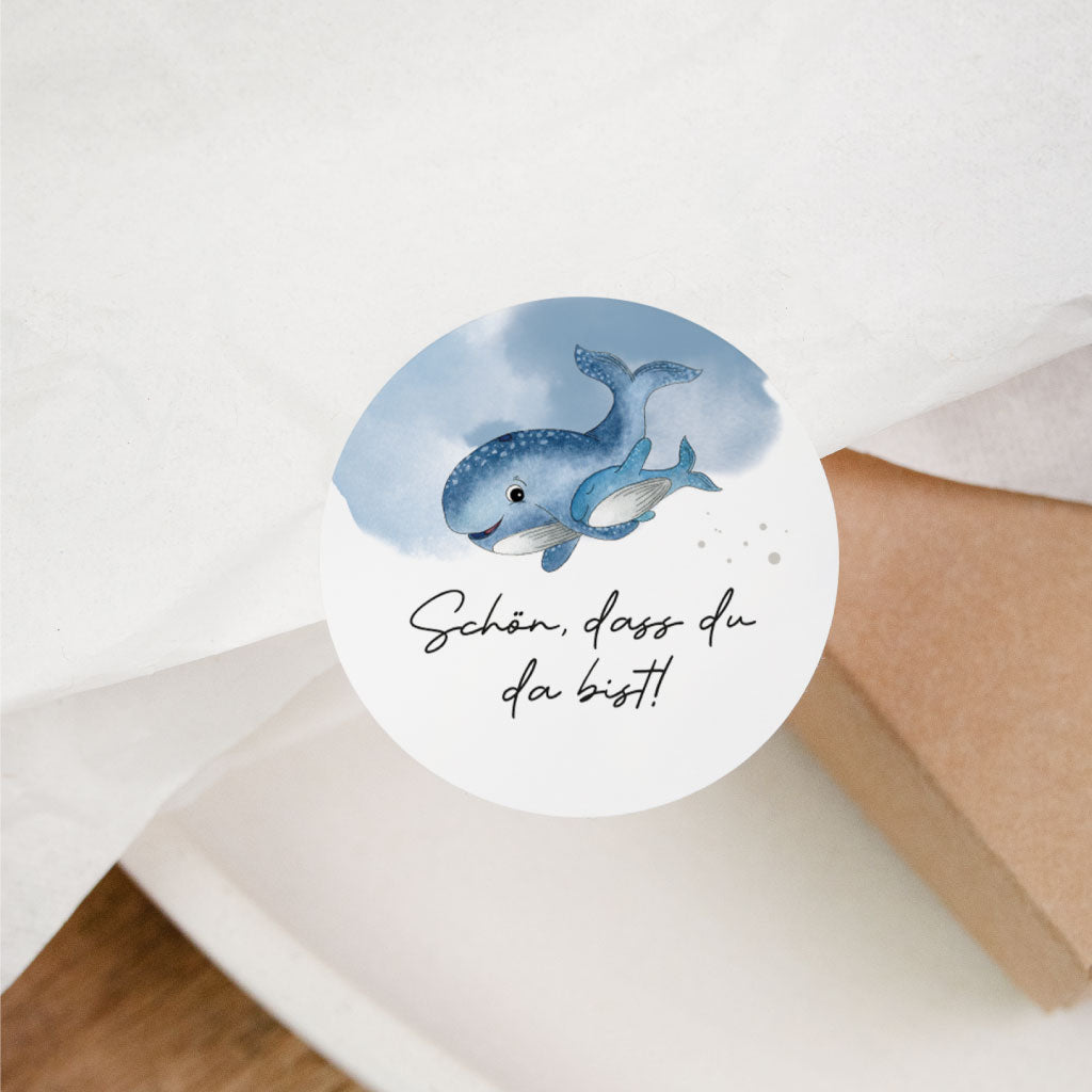Sticker „Schön, dass du da bist“ auf Geschenkverpackung – runder Aufkleber mit zwei Walen für Gastgeschenke bei Hochzeit, Geburtstag oder Taufe