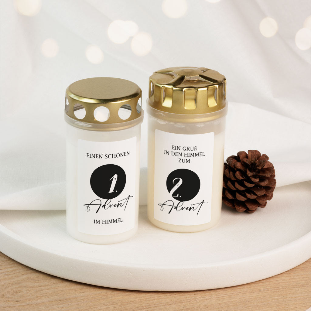 Zwei Grabkerzen mit den Adventsaufklebern für den 1. und 2. Advent, liebevoll dekoriert mit Tannenzapfen – ein stilvoller Grabschmuck zur Weihnachtszeit.