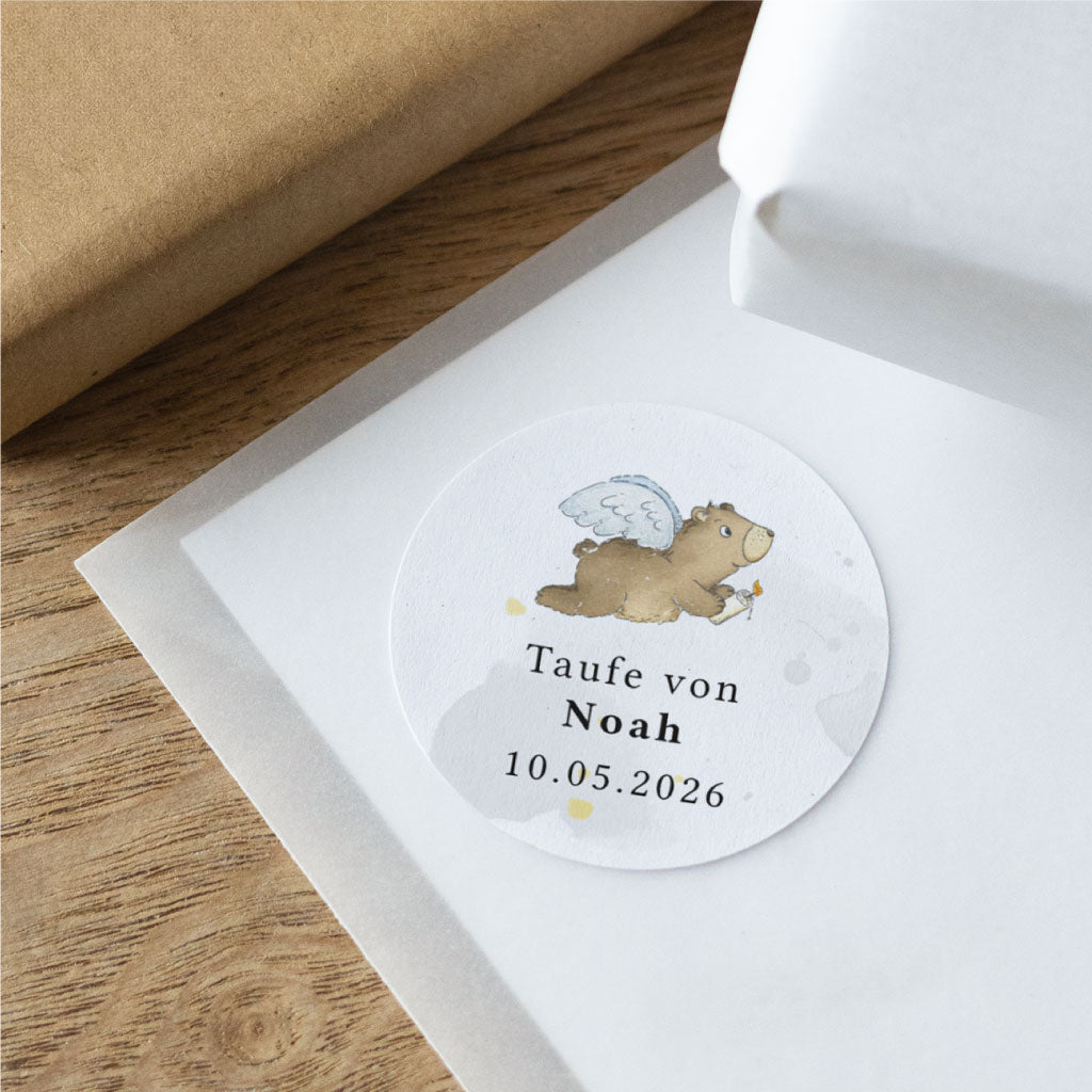 Detailaufnahme eines personalisierten Taufe Aufklebers mit Engel-Bär auf strukturierter Oberfläche, individuell mit Name und Datum