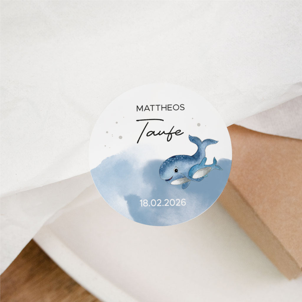 Personalisierter Aufkleber für Taufe auf Geschenkschachtel geklebt, mit Aquarell Wale Motiv, Name und Datum – ideal für Einladungen, Sticker und Gastgeschenke.