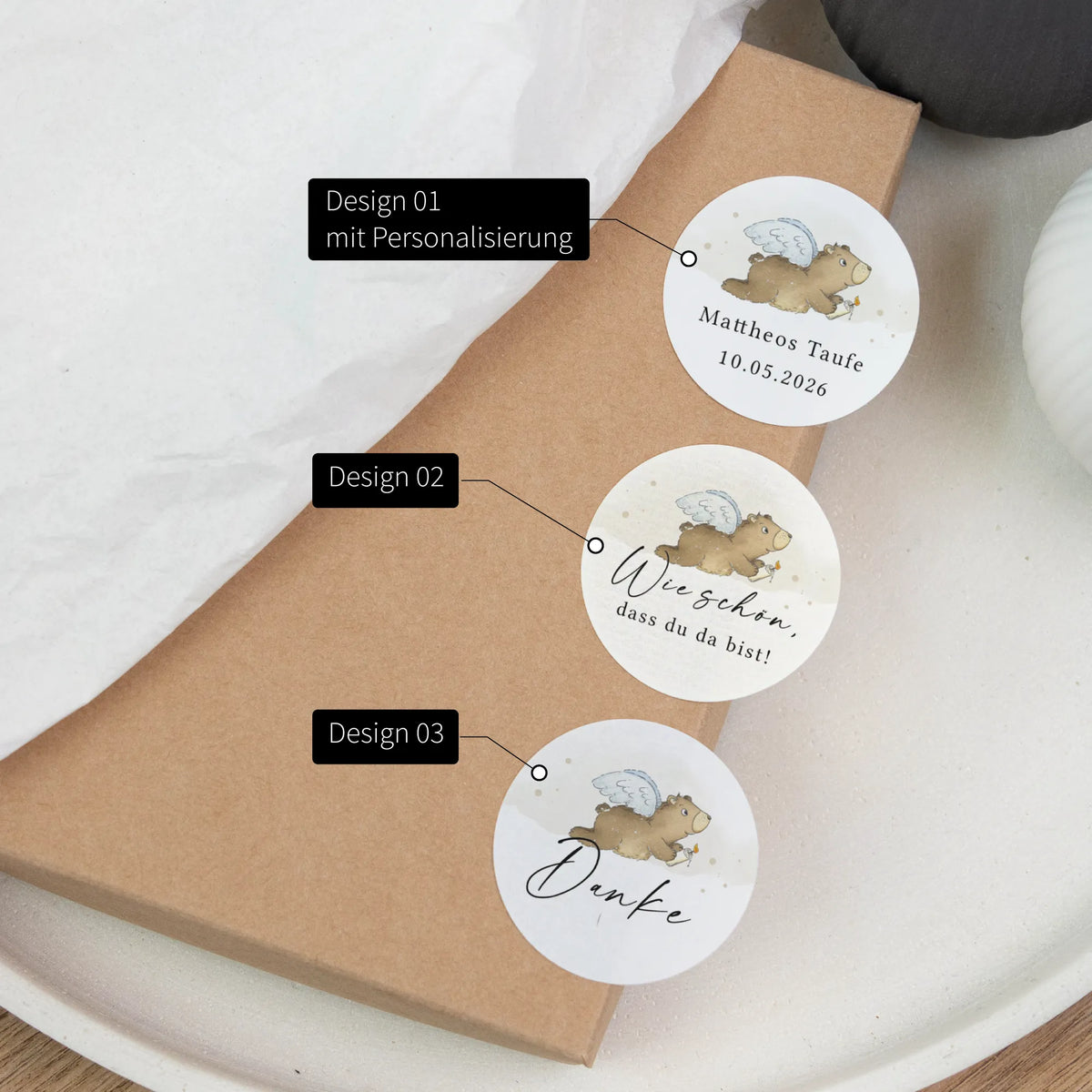 Drei runde Taufe Aufkleber mit Aquarell Motiv Engelbär auf Kraftpapierbox: Design 01 personalisiert, Design 02 Wie schön, Design 03 Danke