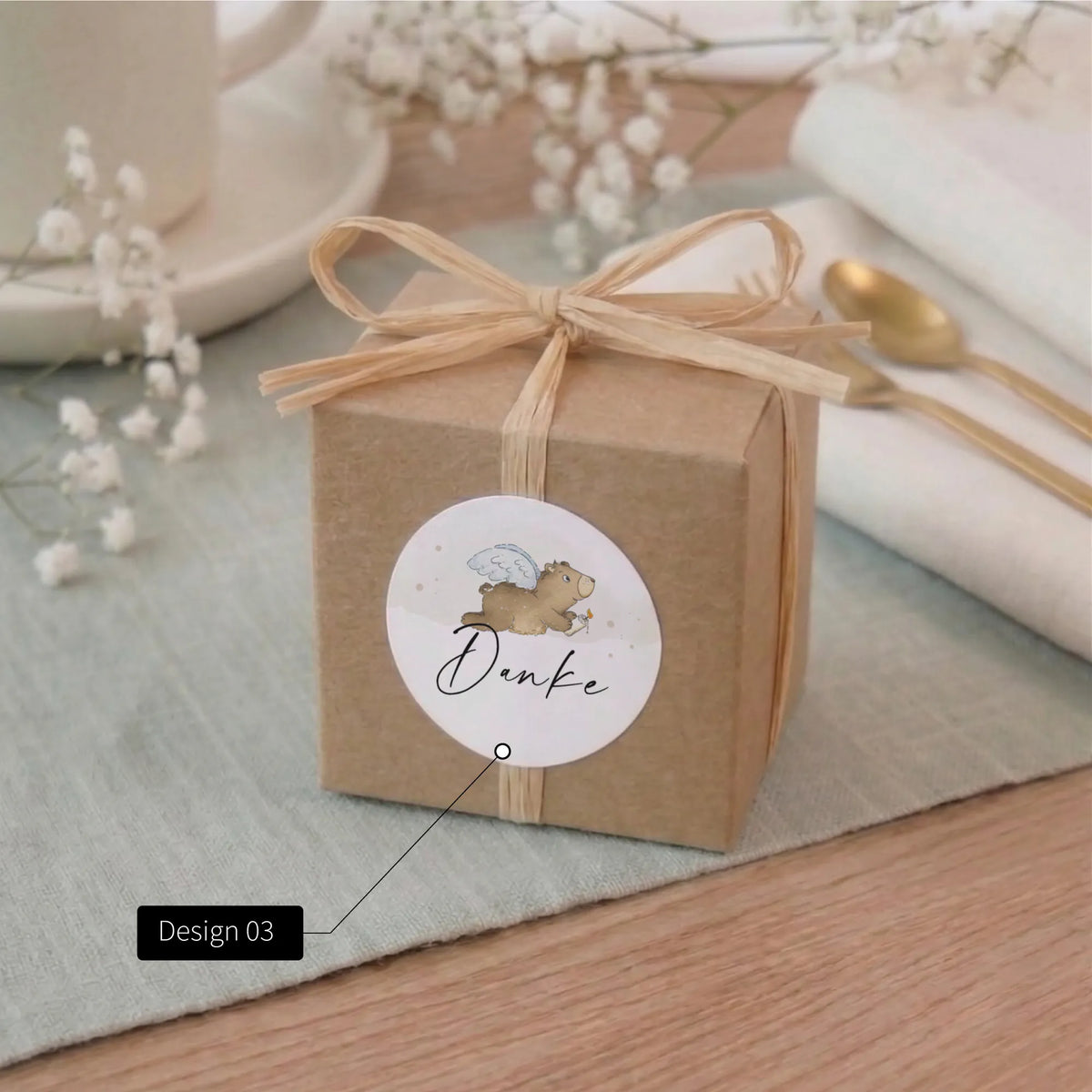 Runder Taufe Aufkleber mit Aquarell Motiv Engelbär und Aufschrift Danke auf Kraftpapier-Geschenkbox mit Bast-Schleife als Gastgeschenk