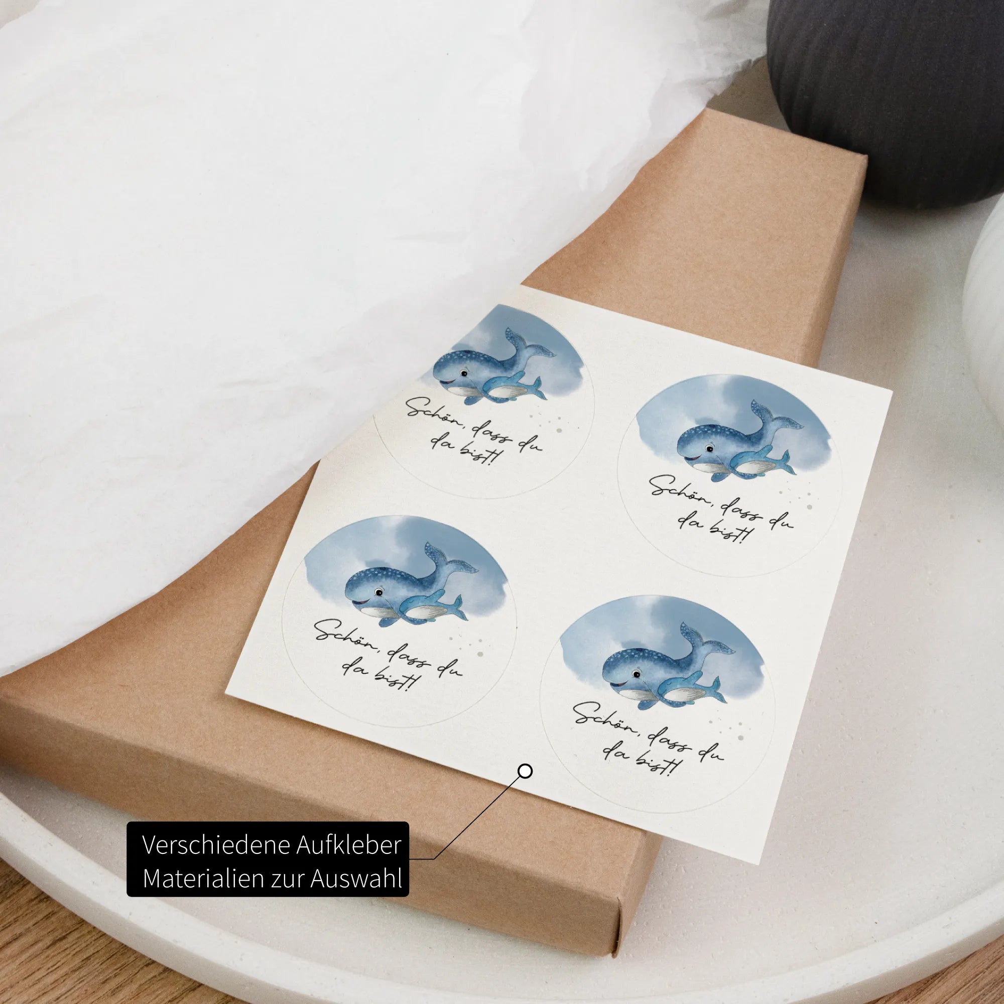 Vier runde Aufkleber zur Taufe mit Aquarell Motiv blauem Wal und Aufschrift Schön dass du da bist auf Geschenkkarton, verschiedene Materialien
