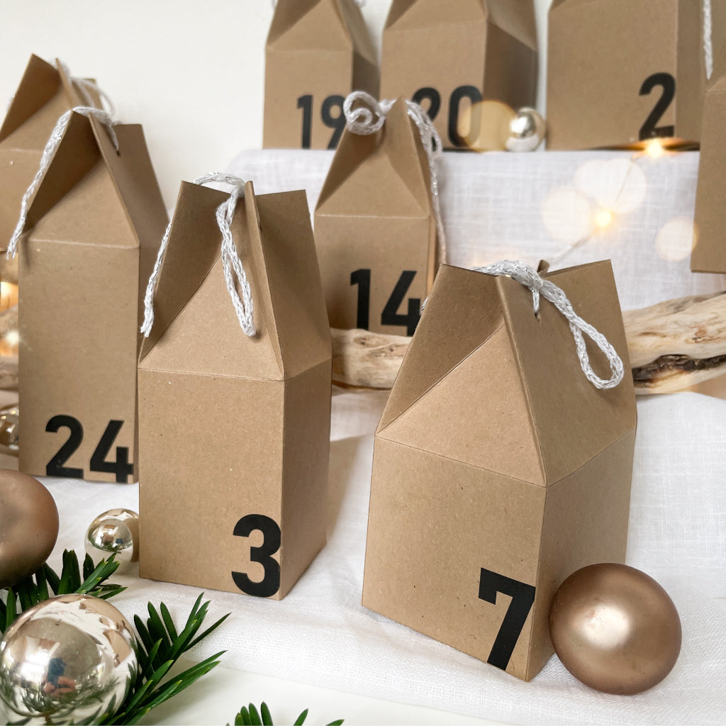 Kreatives DIY Set für einen selbstgemachten Adventskalender mit schlichten Häuschen aus Naturkarton und großen Zahlen.