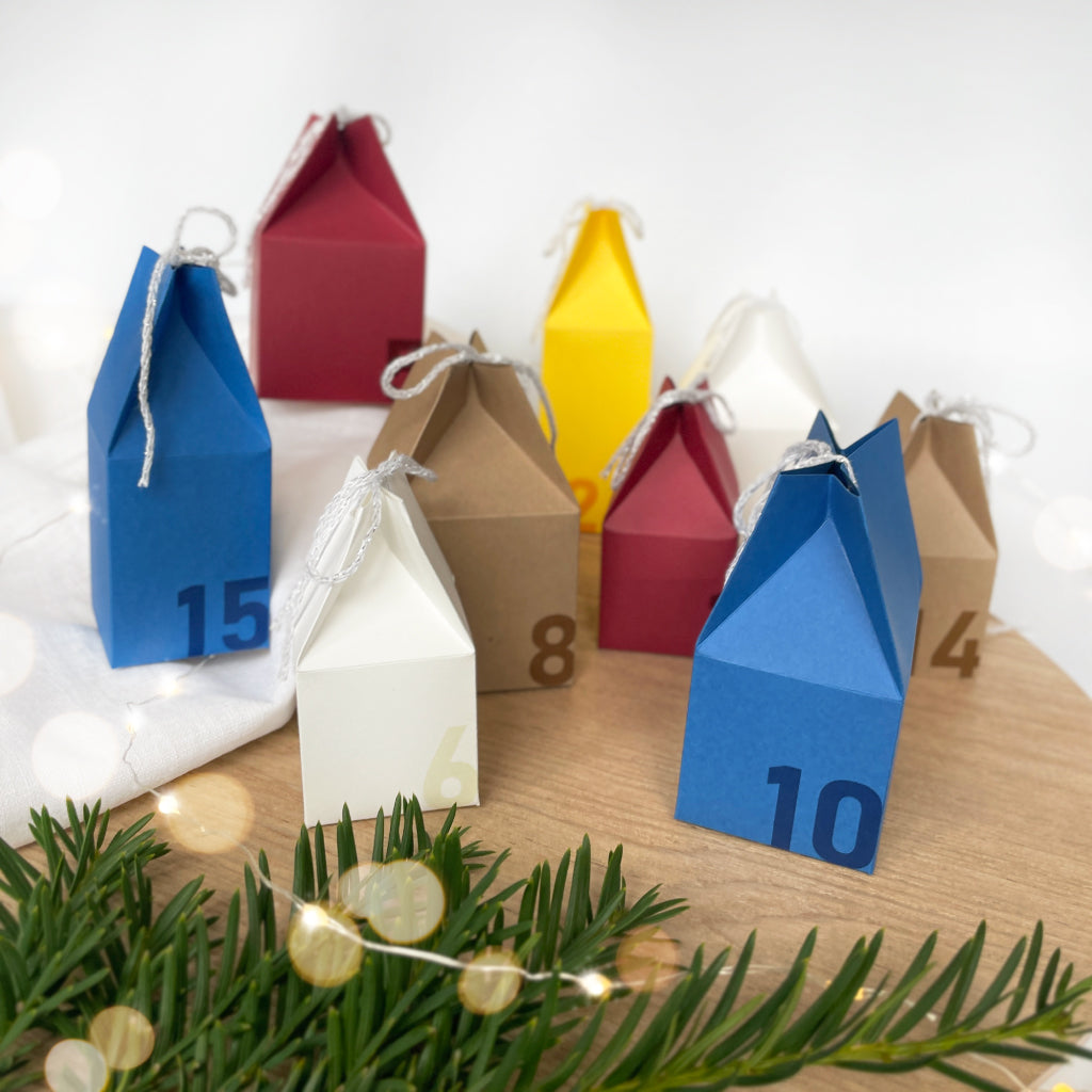 Kreatives Bastelset für die Adventszeit: farbige Adventskalenderhäuser aus Karton mit Zahlen, perfekt zum Selbermachen und Verschenken.