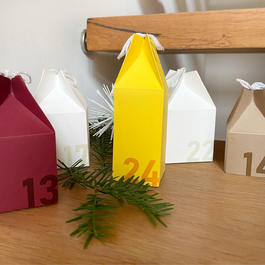 Weihnachtlich dekorierte Adventshäuschen aus Kraftkarton – Variante des Bastelsets für natürliche DIY-Adventskalender.