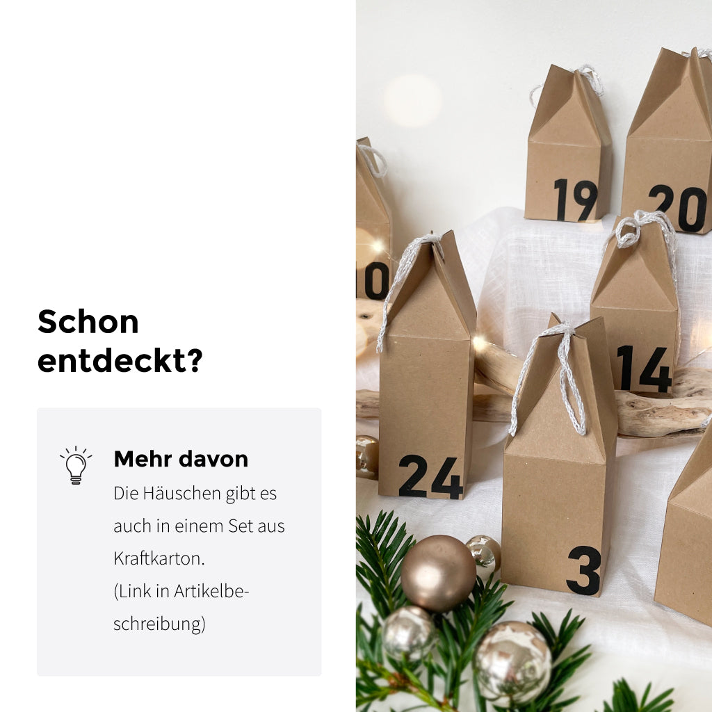 Adventskalender-Häuschen aus Kraftkarton als natürliche Variante des DIY Sets, dekorativ aufgestellt mit Weihnachtskugeln und Tannenzweigen.