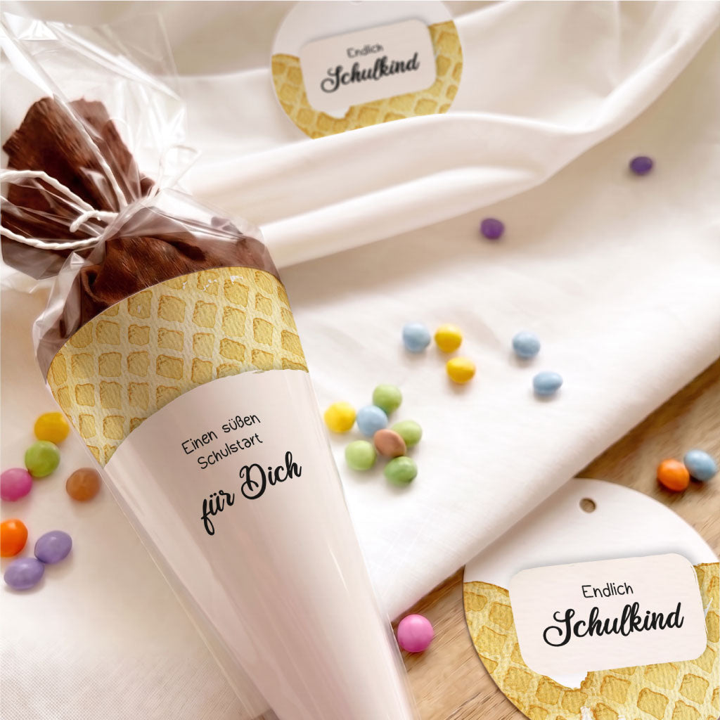 Schultüte für den Schulstart mit Waffel Aquarell Motiv und Anhänger auf hellem Holzuntergrund fotografiert.