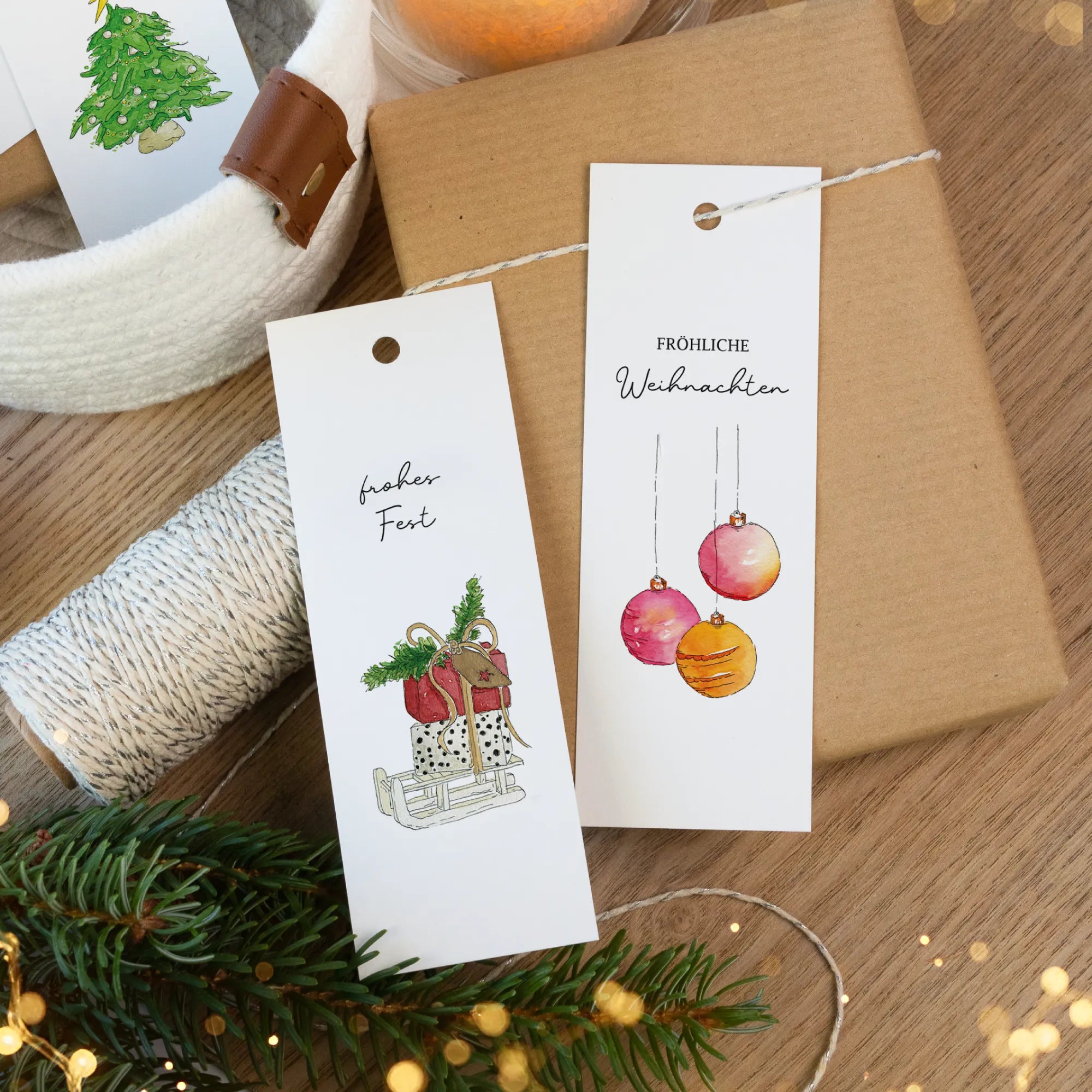 Gedruckte Weihnachtsanhänger mit Aquarell Motiv Geschenke und Christbaumkugeln auf braunem Paket.