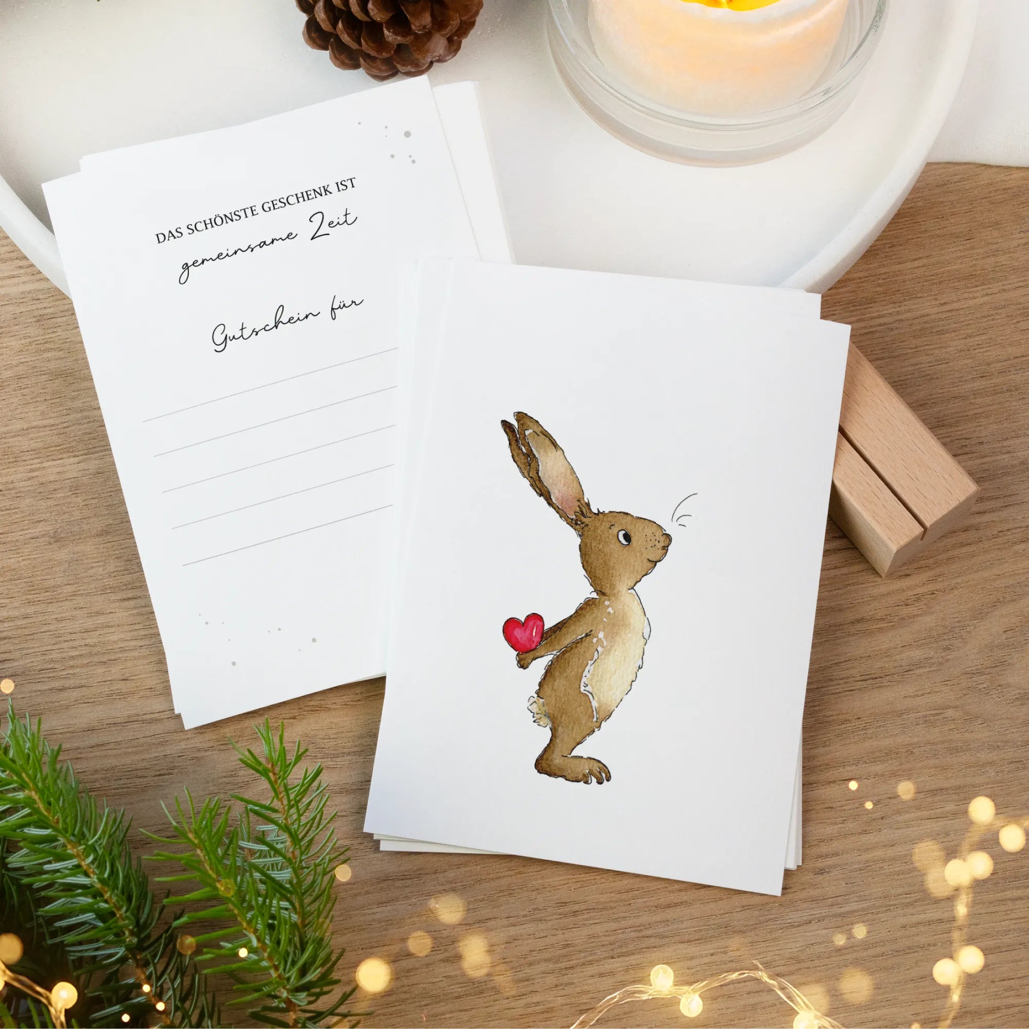 Zwei Gutscheinkarten auf einem Holztisch. Vorne ein handgemaltes Hase Aquarell Motiv und hinten Linien zum Ausfüllen.