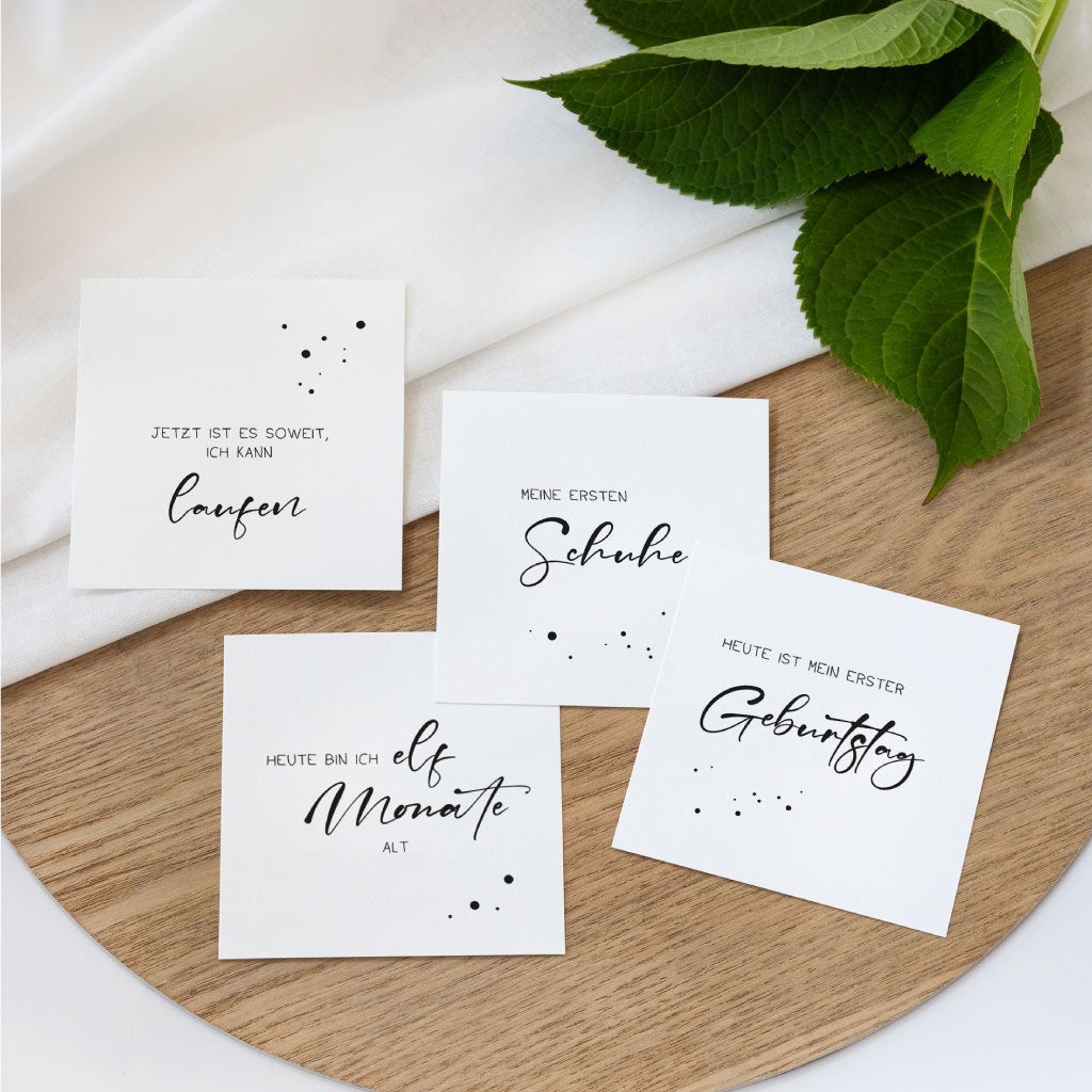 Vier Meilensteinkarten auf Holztablett: „laufen“, „meine ersten Schuhe“, „elf Monate“ und „erster Geburtstag“ – Download Meilensteinkarten digitale Datei fürs Baby erstes Jahr, perfekt zum Fotos machen.