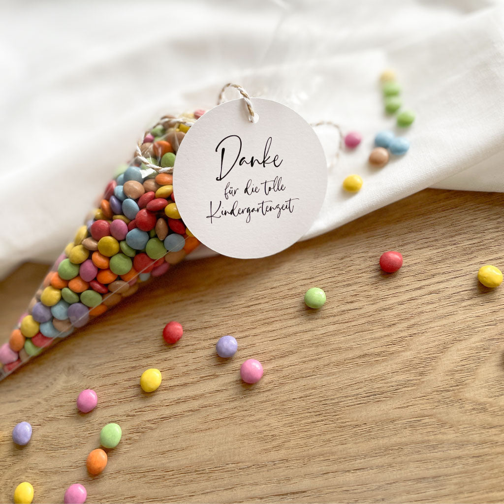 Spitztüte mit bunten Schokolinsen gefüllt, daran Anhänger mit Handlettering Schriftzug