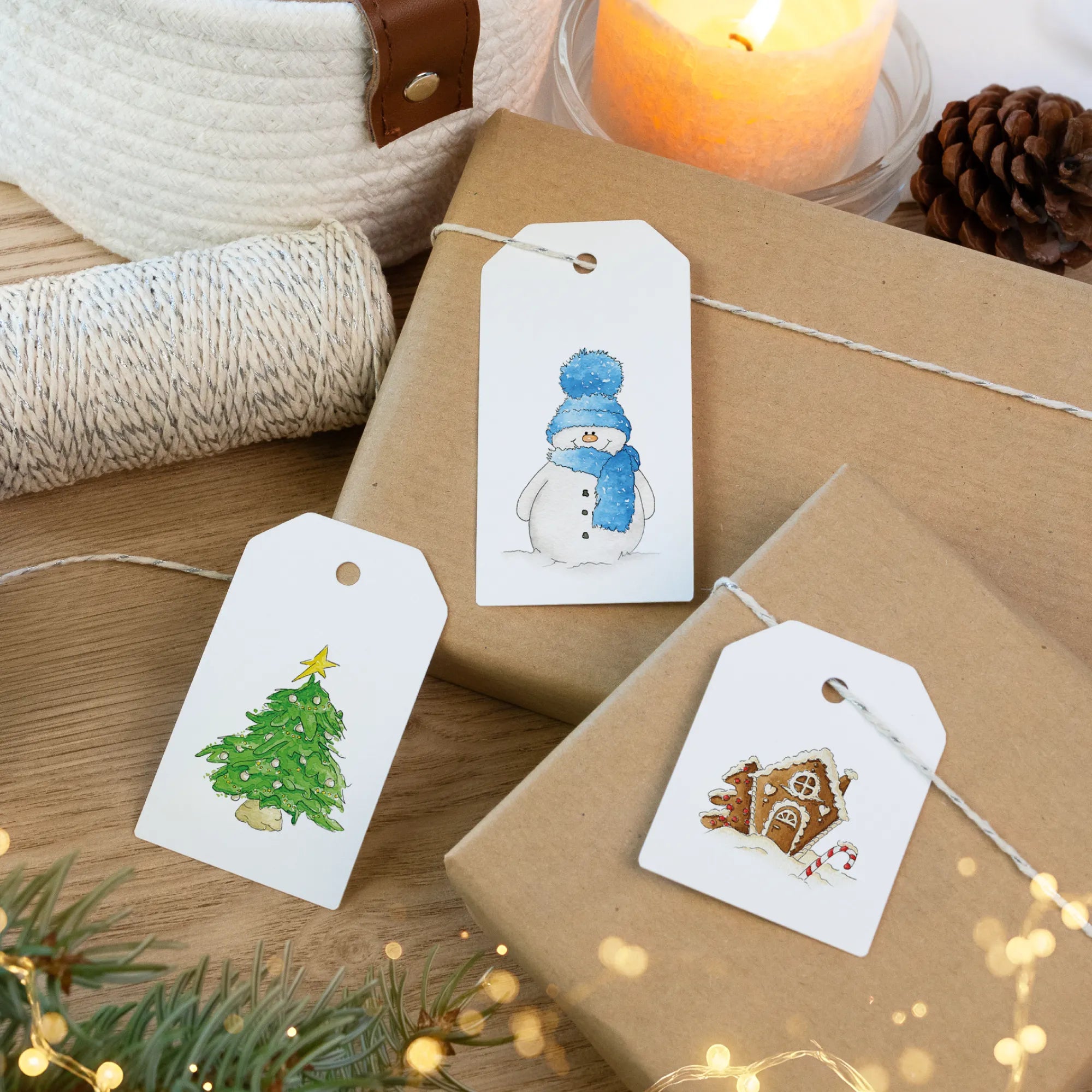 Drei Weihnachtsanhänger mit Tannenbaum und Schneemann Aquarell Motiv auf braunem Geschenk verpackt.