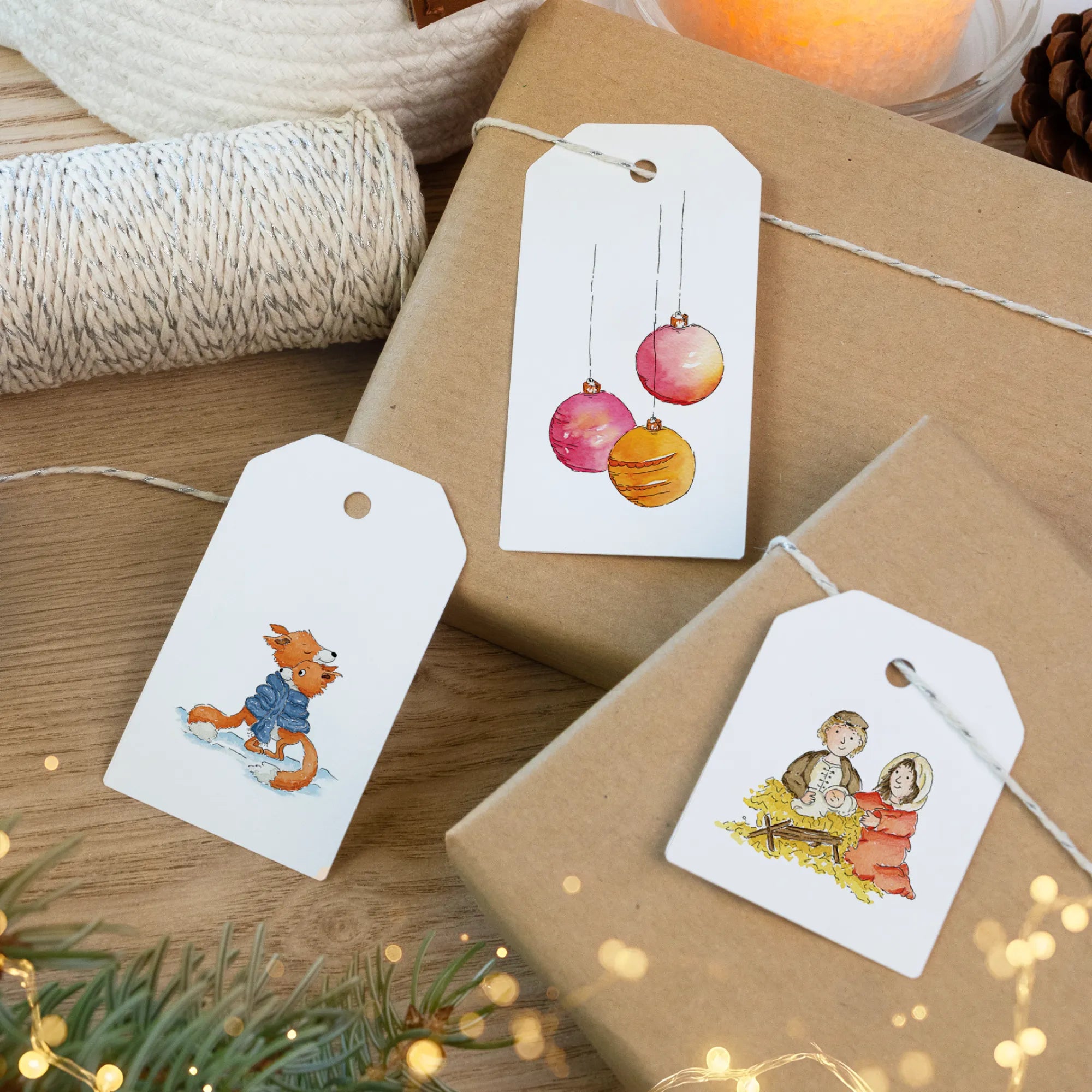 Weihnachtsgeschenke verpackt mit Anhängern die eine Krippe und bunte Christbaumkugeln als Aquarell Motiv zeigen.