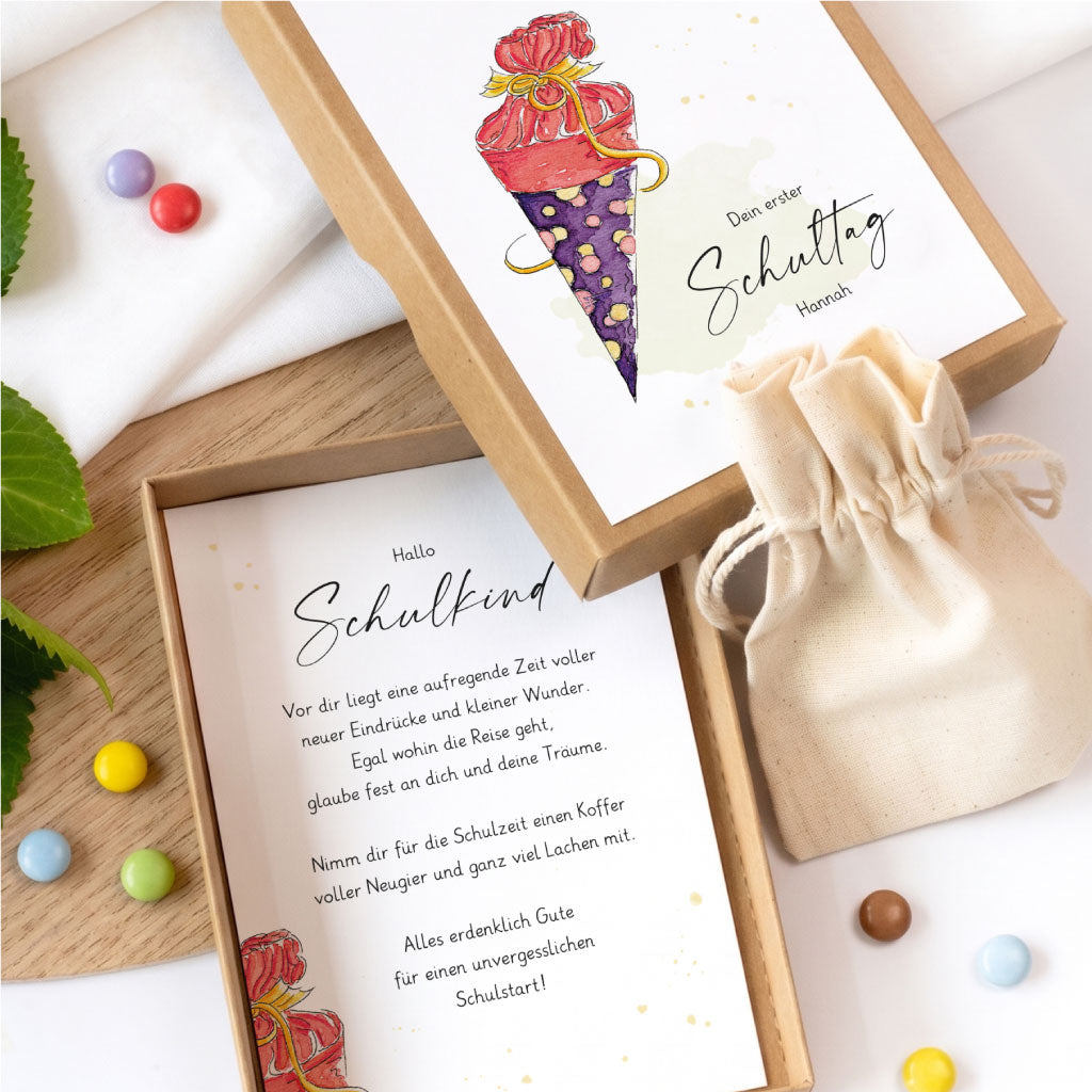Geöffnete Geschenkschachtel für Geldgeschenke zur Einschulung mit Karte und kleinem Baumwollbeutel.