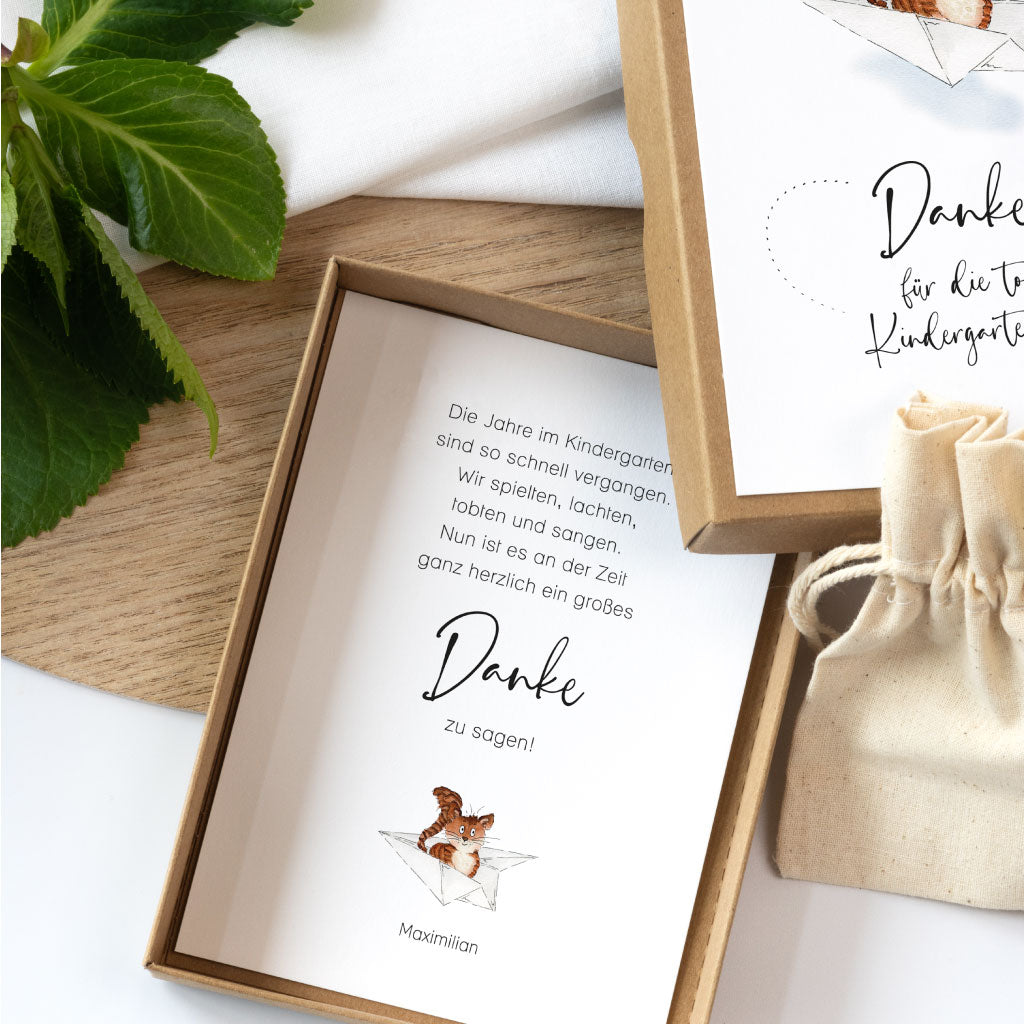 Schachtel aus stabilem Kraftkarton liegt geöffnet da, Deckel mit Spruch "Danke für die tolle Kindergartenzeit"
