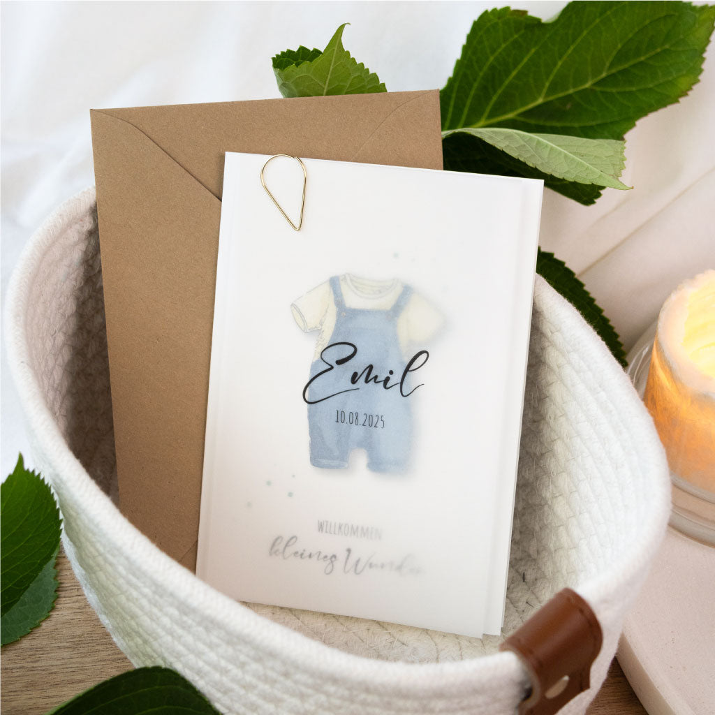 Individuell gestaltbare Geburtskarte mit Aquarell-Strampler in Blau und dem Schriftzug „Willkommen kleines Wunder“, veredelt mit Goldklammer und Transparentblatt.