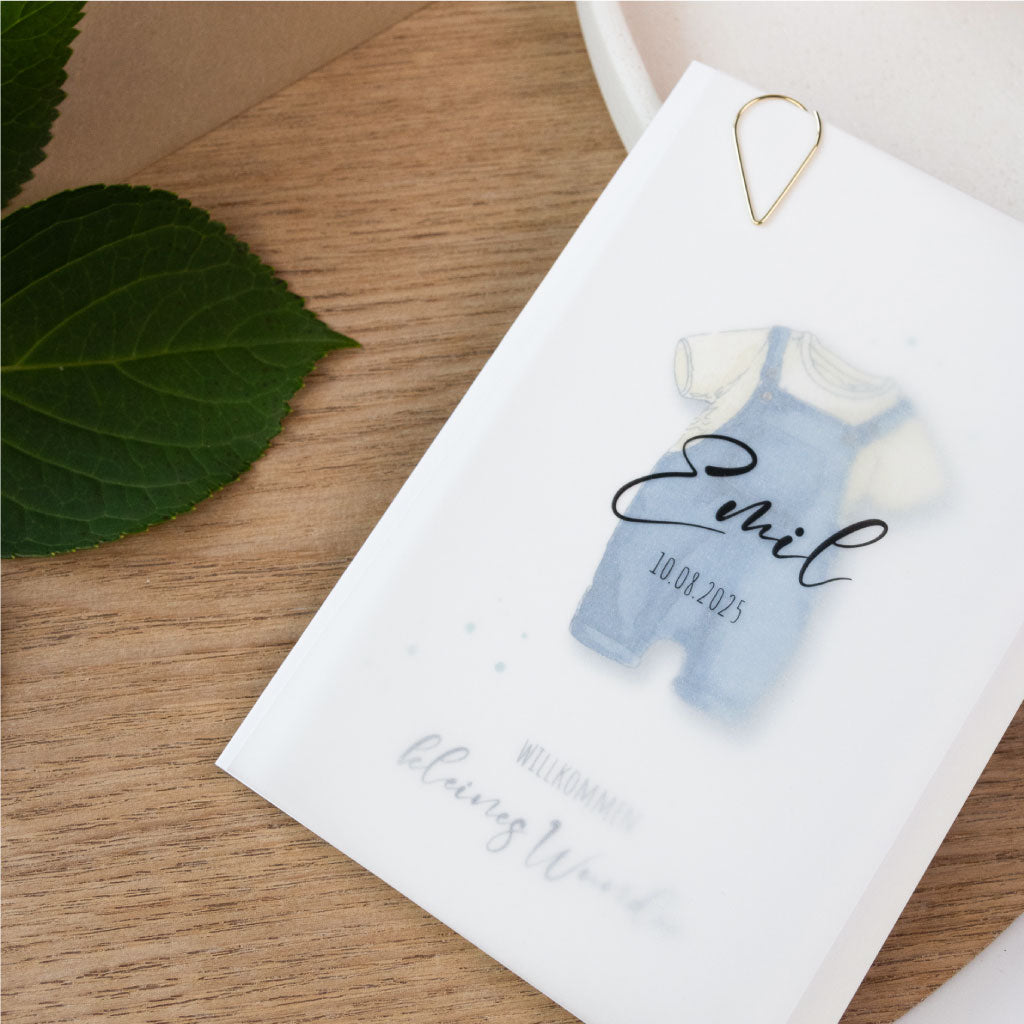 Hochwertige Babykarte zur Geburt mit handgemaltem Strampler-Motiv, personalisiert durch ein transparentes Namensdeckblatt und stilvolle Präsentation.