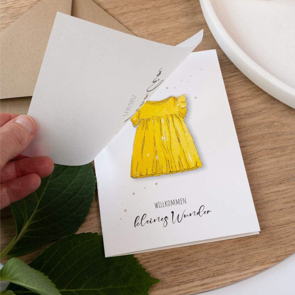 Besondere Babykarte zur Geburt mit liebevoll gemaltem Kleid in Sonnengelb, personalisierbar mit Name und Geburtsdatum, gedruckt auf festem Karton.