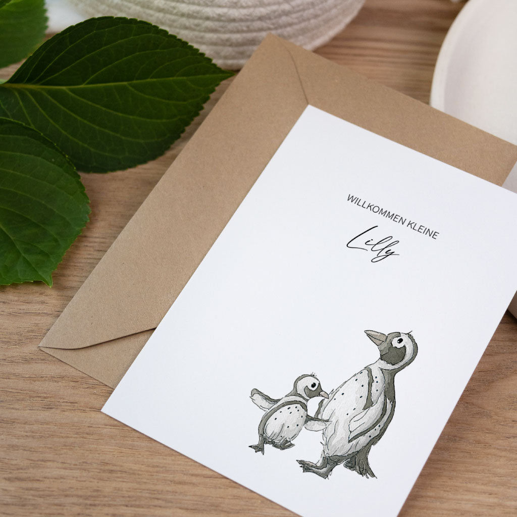 Babykarte mit handgemalten Pinguinen im Aquarellstil, Aufschrift „Willkommen kleine Lilly“ und Umschlag aus Kraftpapier.