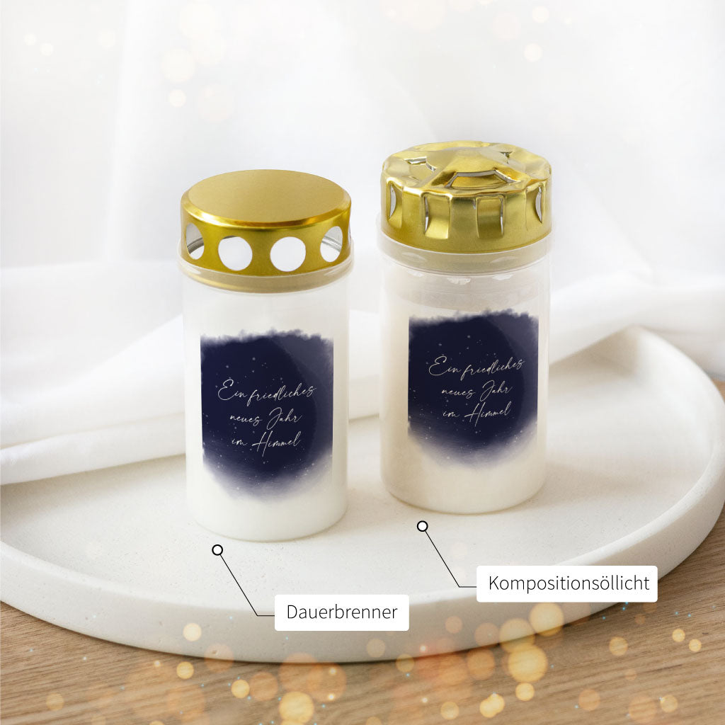 Zwei Varianten der Silvester-Grabkerze mit dunkelblauem Himmel und dem Text „Ein friedliches neues Jahr im Himmel“ – Kompositionsöllicht und Dauerbrenner im Vergleich
