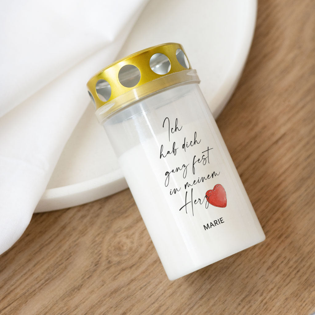 Personalisierbare Grabkerze mit goldfarbenem Deckel und liebevollem Trauerspruch „Ich hab dich ganz fest in meinem Herz“, verziert mit einem handgemalten Aquarell-Herz und dem Namen „Marie“.