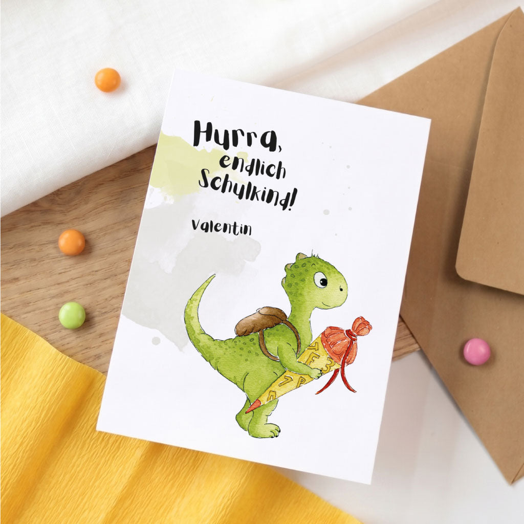 Karte zur Einschulung mit grünem Dino Aquarell Motiv und Name Valentin auf weißem Hintergrund.