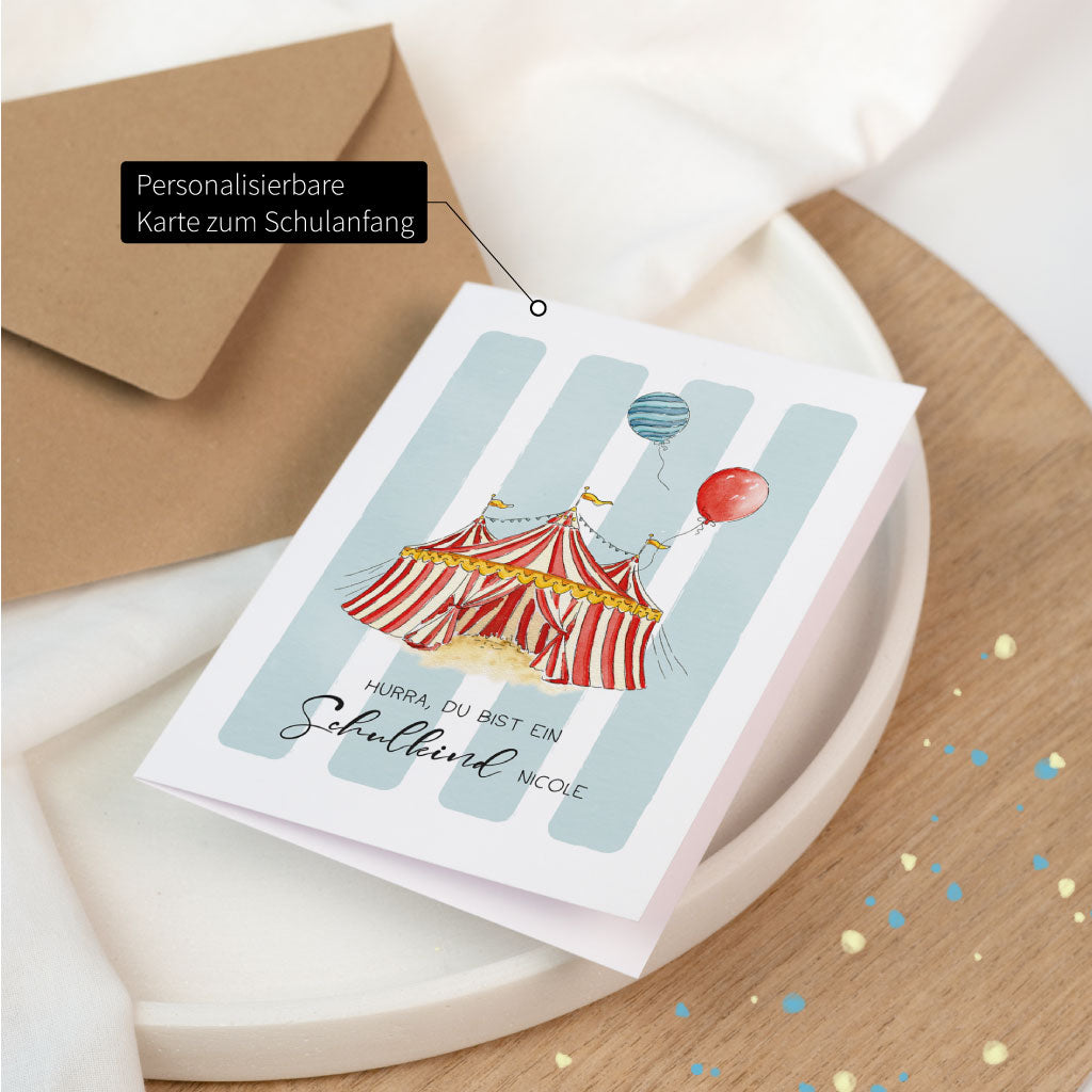 Personalisierbare Karte zum Schulanfang – Glückwunschkarte zur Einschulung mit Namen personalisierbar, Zirkus-Zelt auf blau gestreiftem Hintergrund.