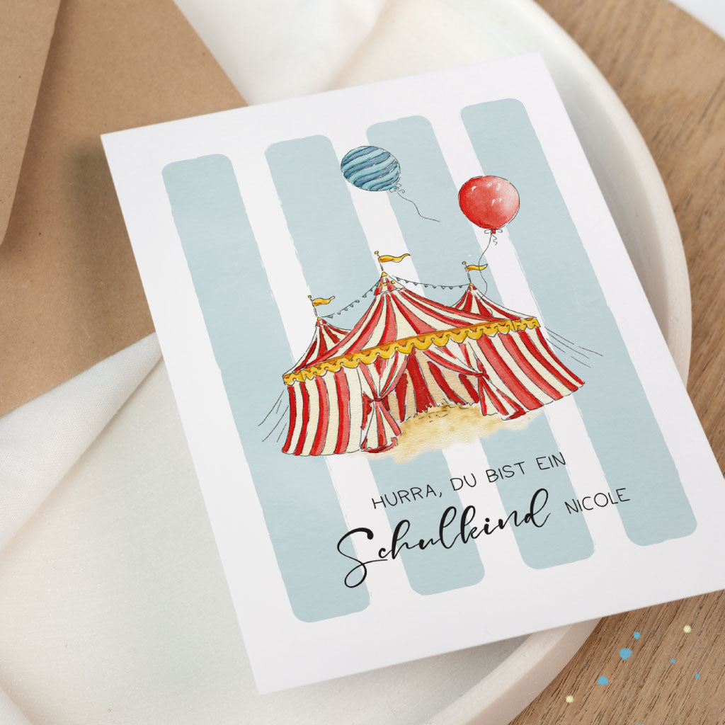Glückwunschkarte zur Einschulung im Zirkus-Design, Nahaufnahme der Karte: Schulanfang-Motiv mit rot-weißem Zelt und Ballons, mit Namen personalisierbar.