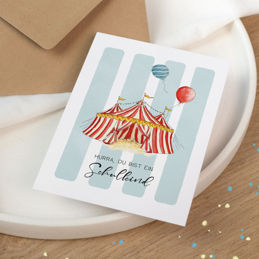 Glückwunschkarte zur Einschulung: Karte zum Schulanfang mit Zirkus-Zelt und Ballons, Schriftzug „Hurra, du bist ein Schulkind“.