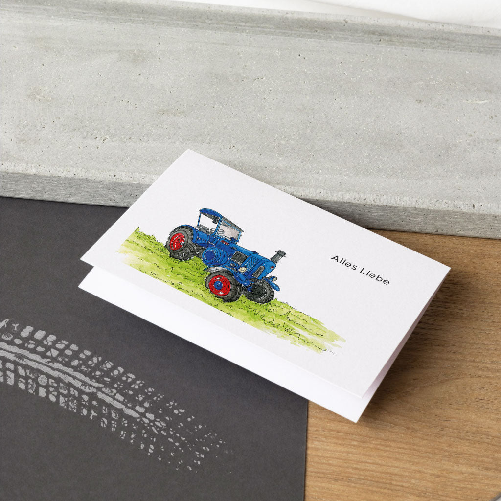 Klappkarte aufgeklappt mit blauem Trecker Motiv in grüner Wiese