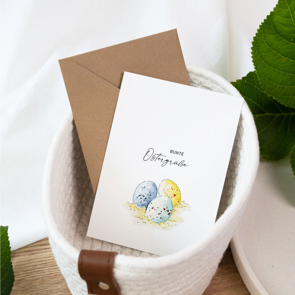 Aquarell Postkarte zu Ostern mit handgemalten Ostereiern auf Stroh, schlichte Osterkarte für das Osterfest.