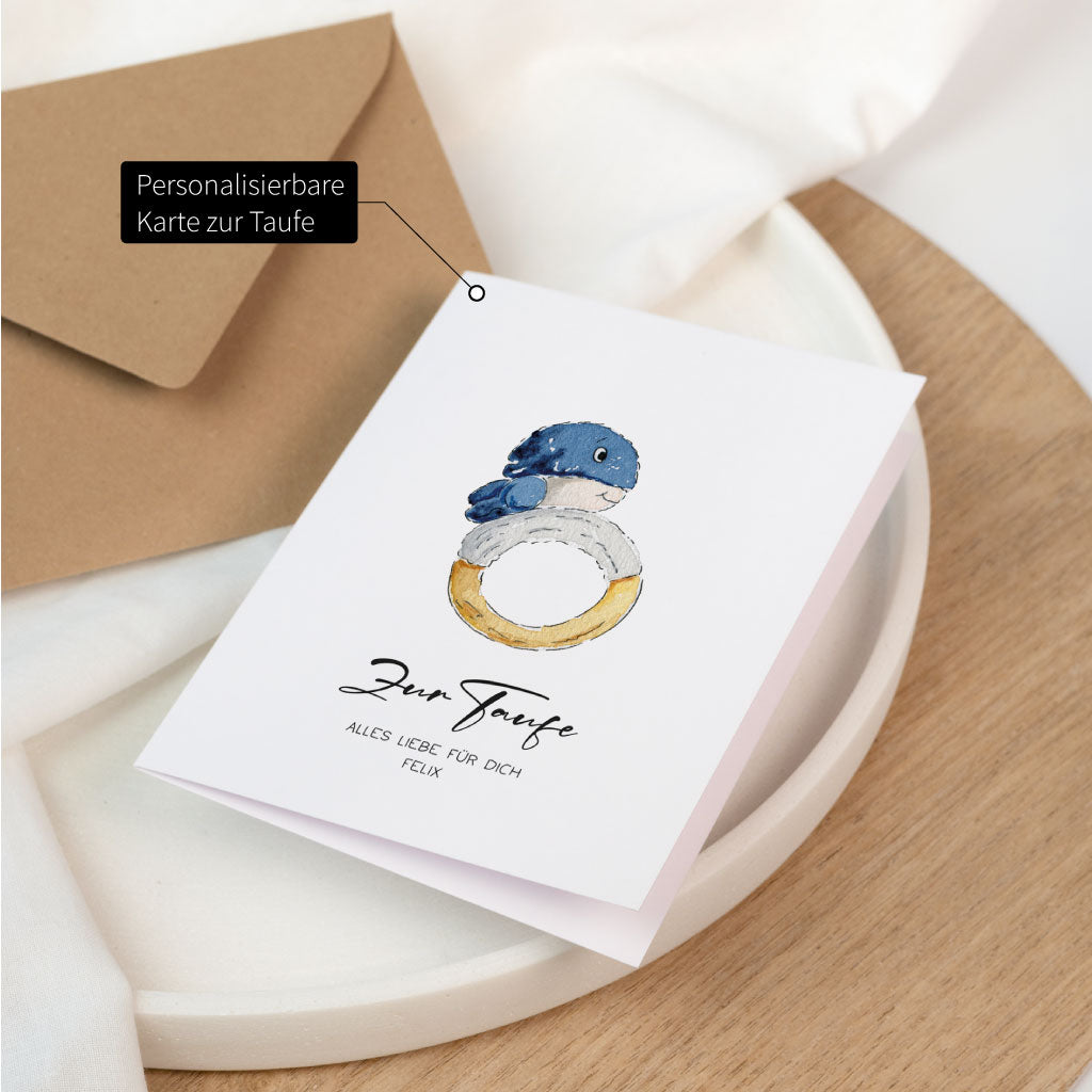 Aufgeklappte Glückwunschkarte zur Taufe mit handgemaltem Wal, personalisierbar mit Name, neben braunem Umschlag