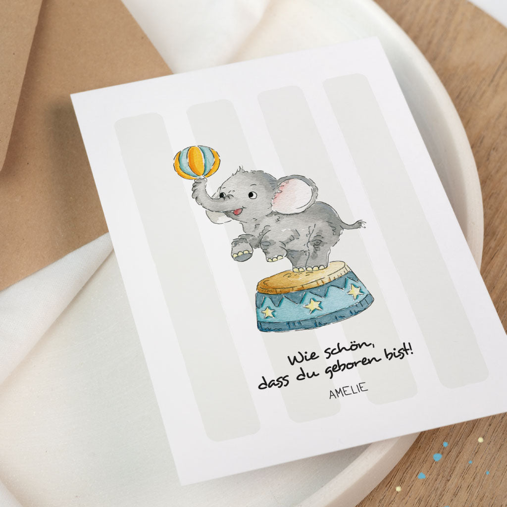 Nahaufnahme der Glückwunschkarte zur Geburt eines Babys: Elefant mit Ball auf Zirkus-Trommel, Schriftzug „Wie schön, dass du geboren bist!“, mit Name personalisierbar.