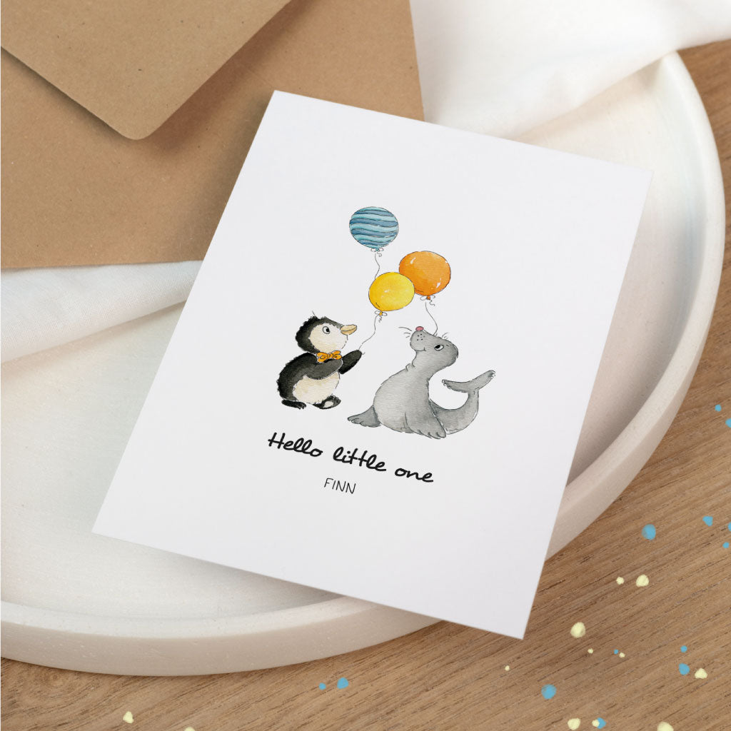 Personalisierbare Glückwunschkarte zur Geburt Baby mit handgemaltem aquarell Zirkus-Motiv: süßes Tier Pinguin und Seehund halten bunte Luftballons, „Hello little one“ mit Name.