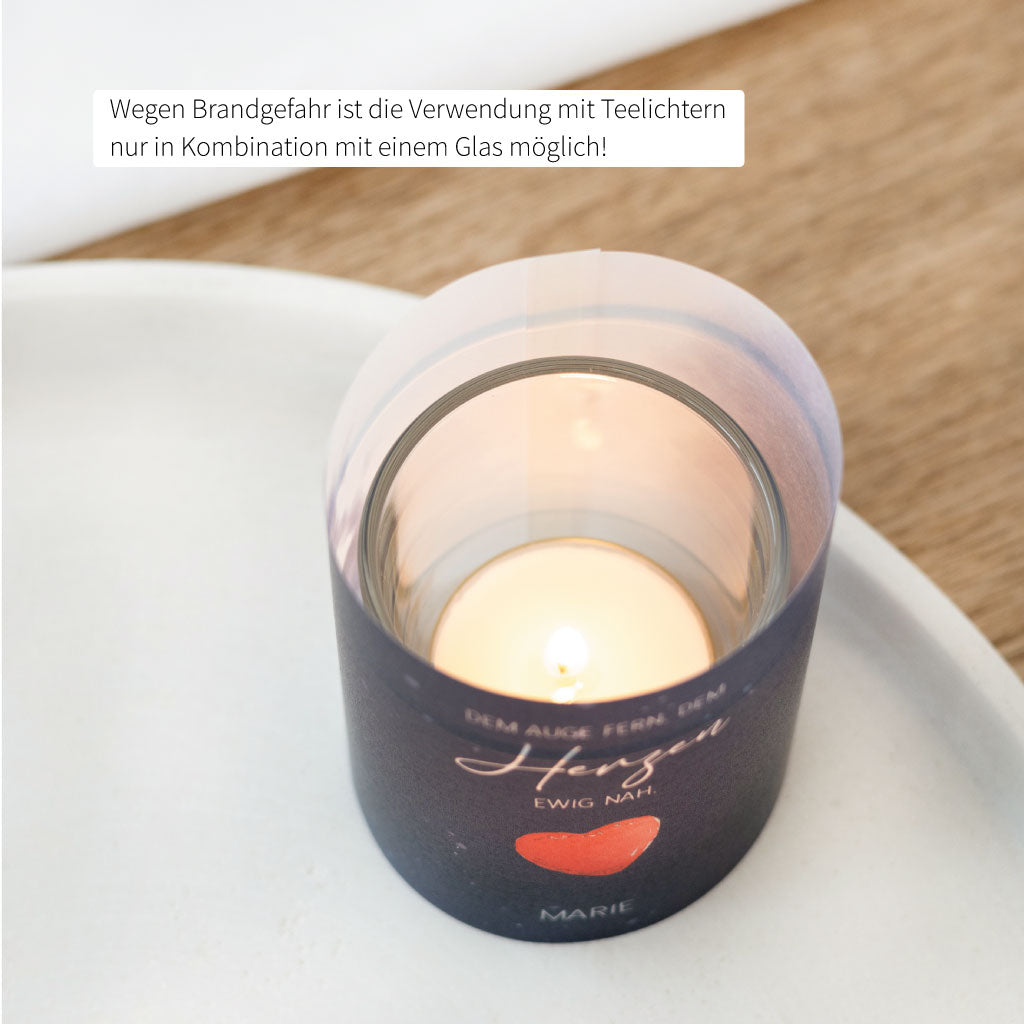 Blick von oben auf das brennende Teelicht im Glas, umhüllt von der bedruckten Trauer-Lichthülle mit Sicherheitsvermerk.