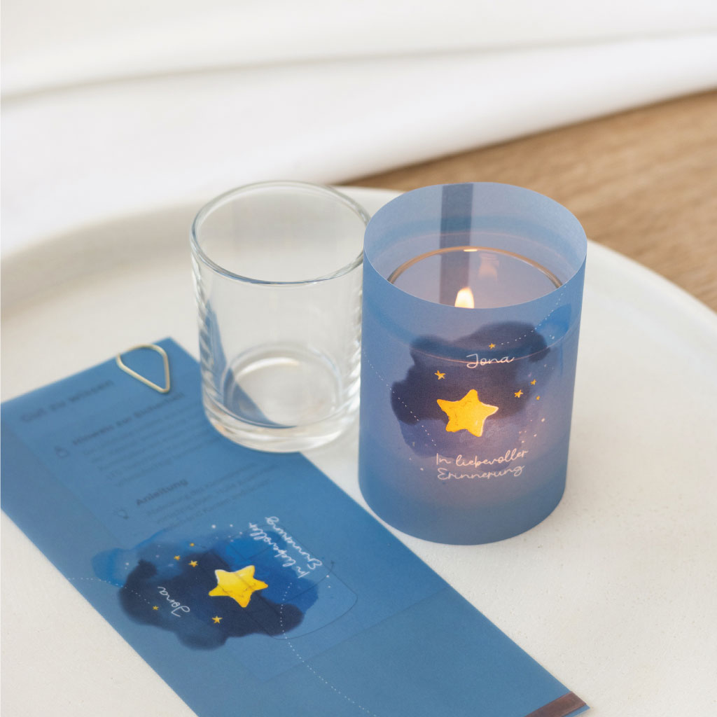 Lichthülle mit Kerze und Glas, daneben flach liegendes Transparentpapier mit Sternenmotiv – vollständiges Set als liebevolle Erinnerung an ein Sternenkind.