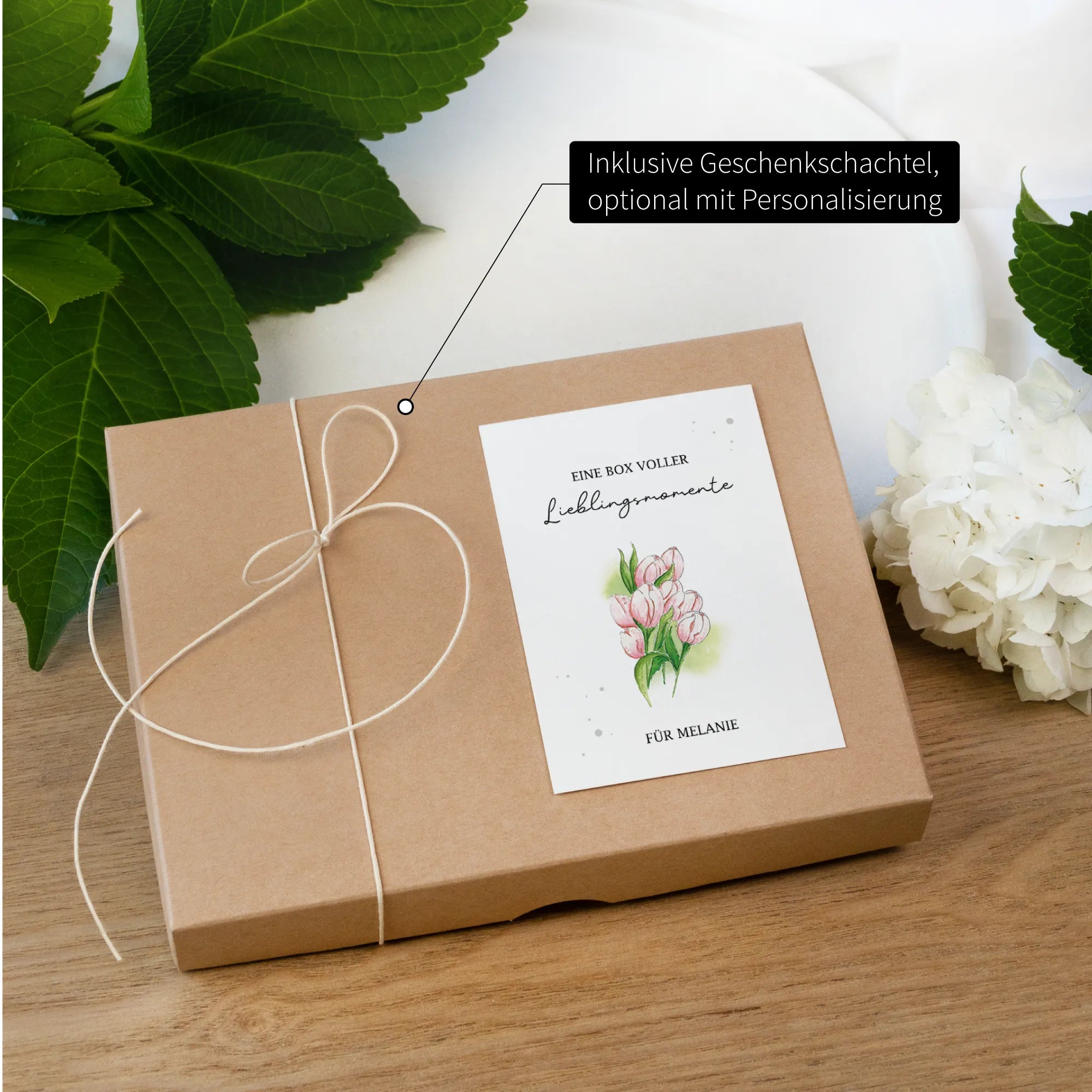 Verschlossene Geschenkschachtel mit personalisierter Banderole. Darauf ein Blumen Aquarell Motiv aus rosa Tulpen gemalt.