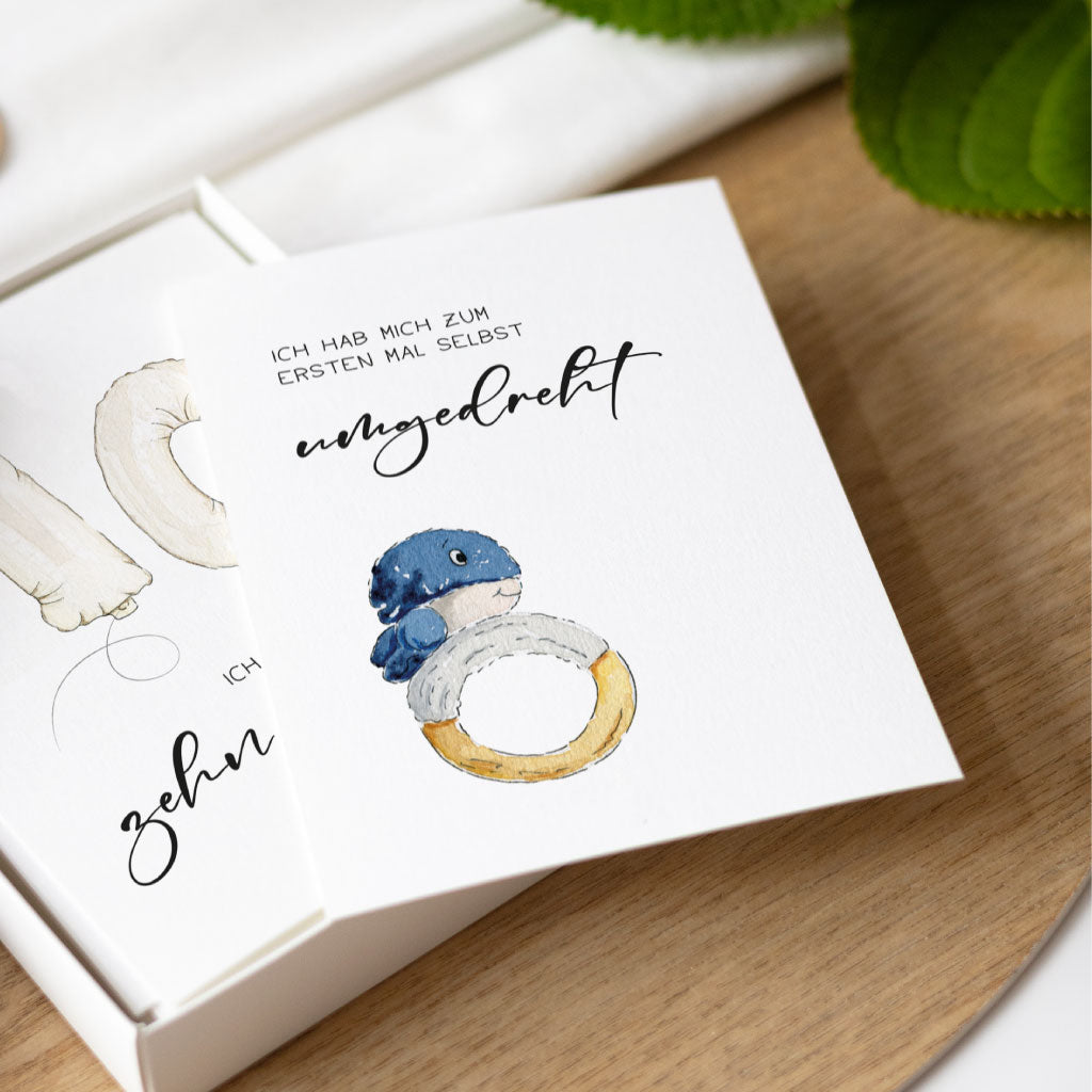 Detailaufnahme einer Meilensteinkarte mit Aquarellmotiv und der Aufschrift „Ich hab mich zum ersten Mal selbst umgedreht“, aus dem Set für Babys 1. Jahr.