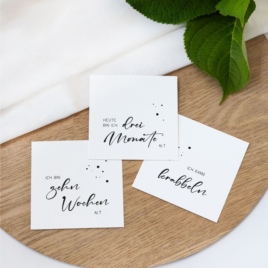 Drei Meilensteinkarten auf Holztablett: „Ich bin zehn Wochen alt“, „Heute bin ich drei Monate alt“ und „Ich kann krabbeln“ – perfekt zum Fotos machen und Erinnerungen festhalten.