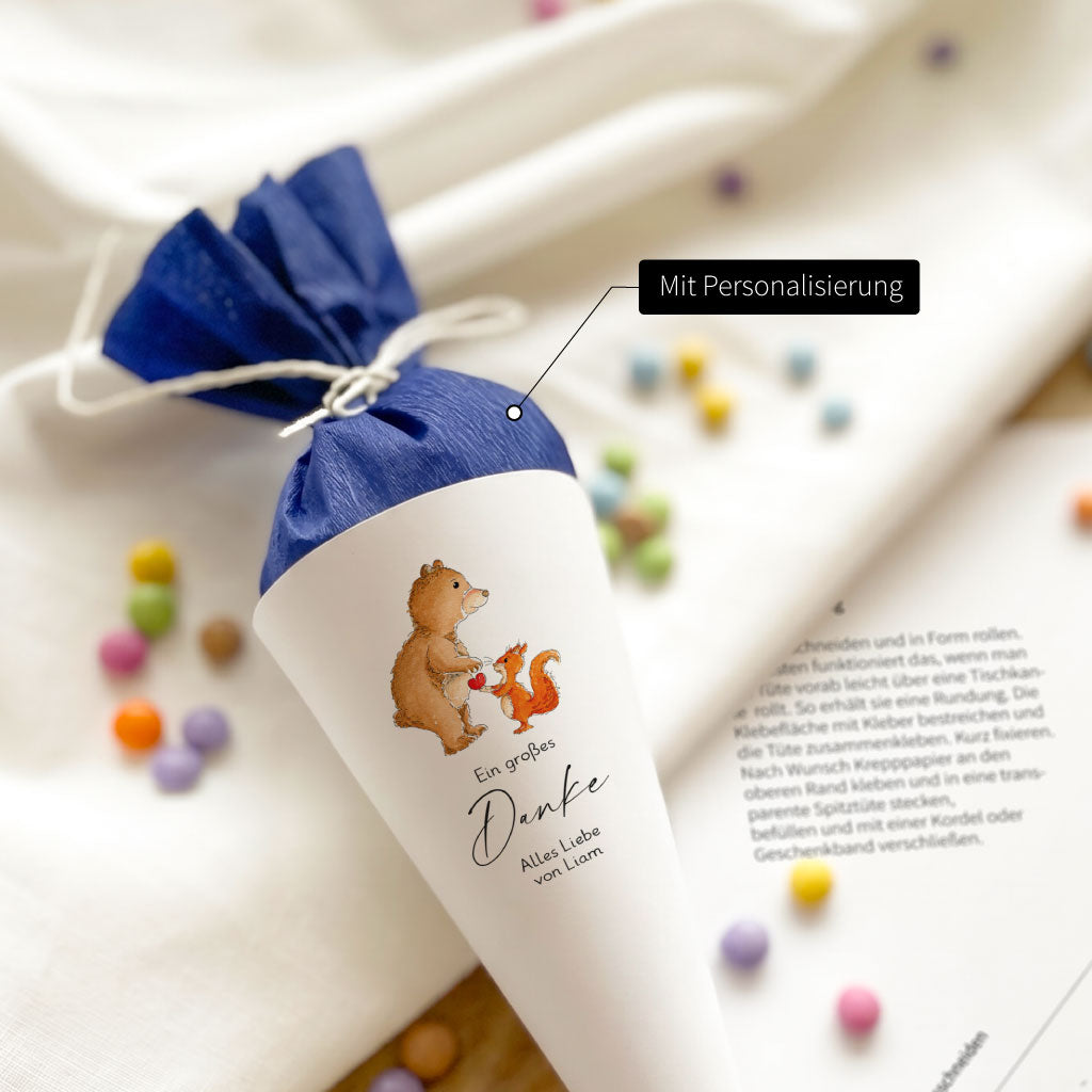 Nahaufnahme der kleinen Schultüte mit Bär und Eichhörnchen Aquarell Motiv und personalisiertem Namenstab für Erzieher.