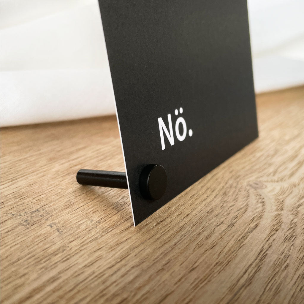 Schwarzer Kartenhalter als Kartenständer: Pop Up Frame Fotohalter magnetisch schwarz, hält eine Karte mit „Nö.“ auf dem Holztisch.