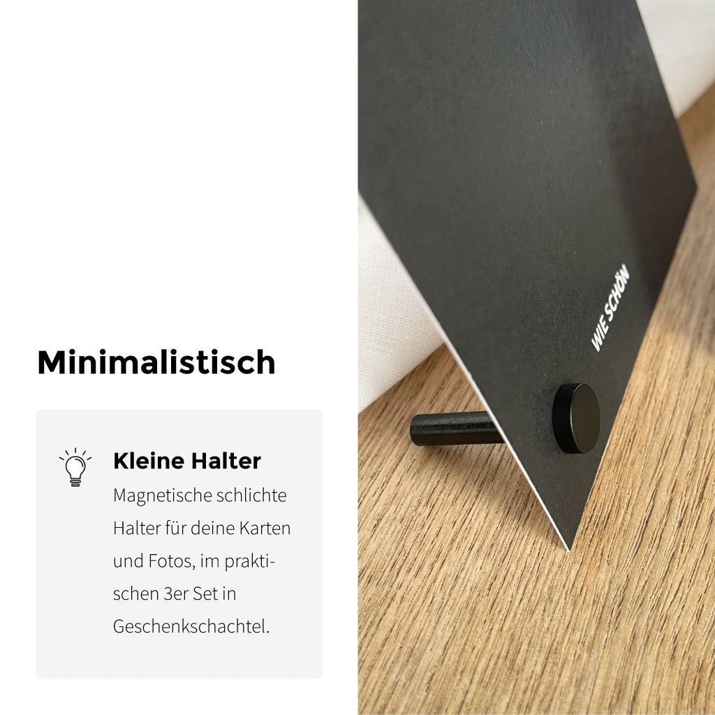 Minimalistisch dargestellter Pop Up Frame Kartenhalter: magnetisch schwarz als Kartenständer für Karten und Fotos, Produktdetail auf Holz.